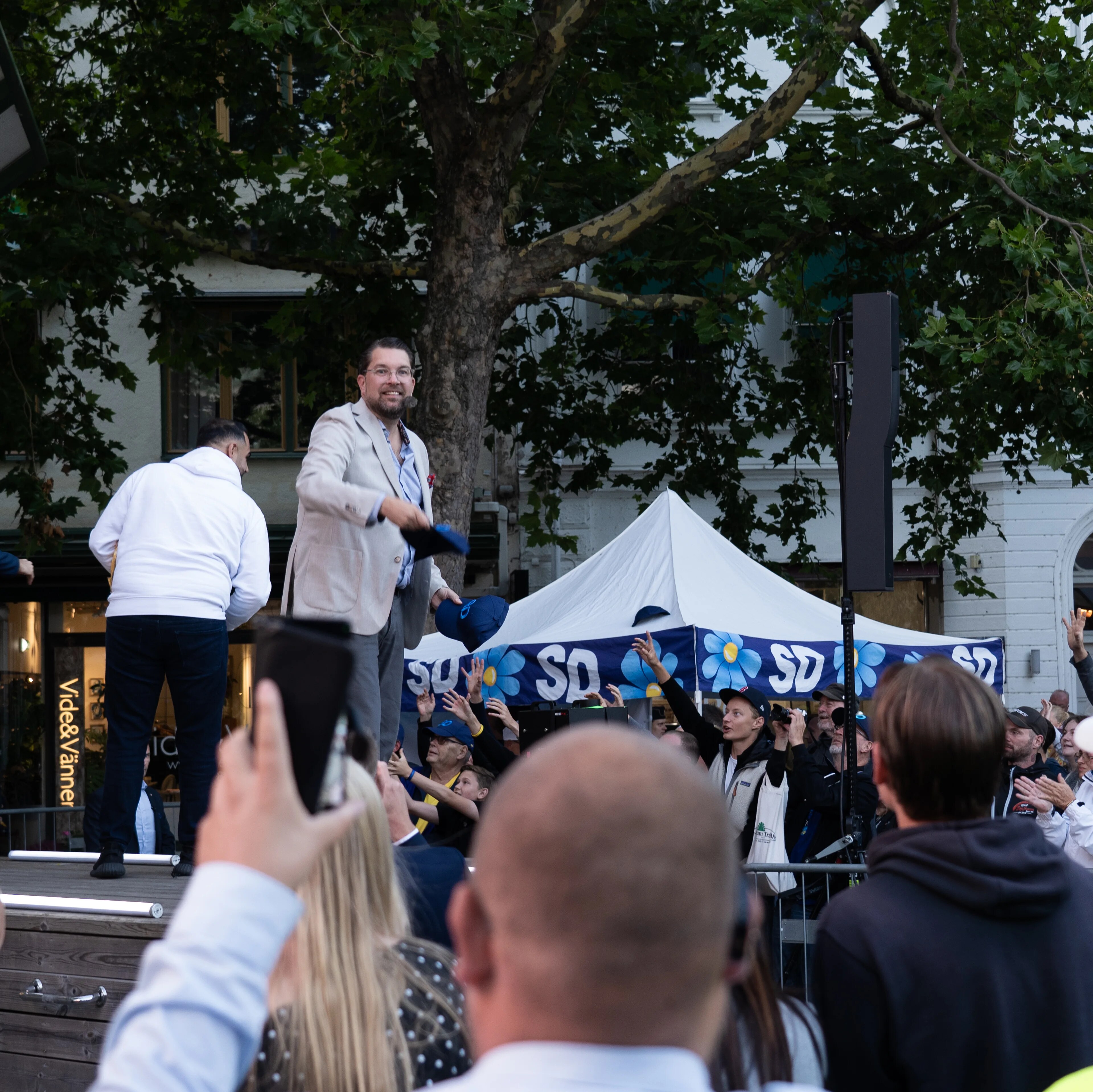 Jimmie Åkesson taler fra en scene foran en folkemengde ved et arrangement for Sverigedemokraterna. (Bildebeskrivelsen er laget av en KI-tjeneste)