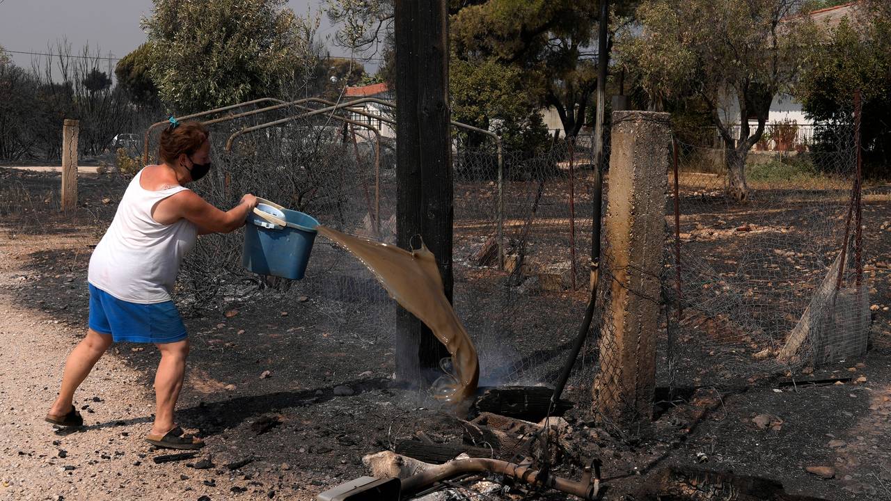 En kvinne laster vann på rykende trær i Varibobi-området, nord i Athen. 