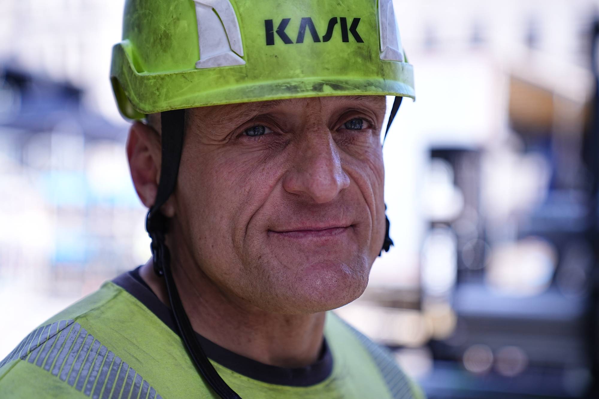 Portrett av en mann iført gul vernehjelm med Kask-logo og gul refleksvest. (Bildebeskrivelsen er laget av en KI-tjeneste)
