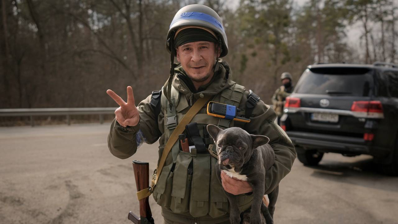 Ukrainsk tjenestemann gjør v-tegn mens han holder en valp.