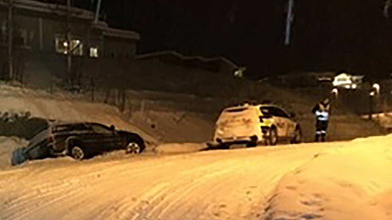 Bil i grøfta på snødekt vei med politi som undersøker iført refleksvest