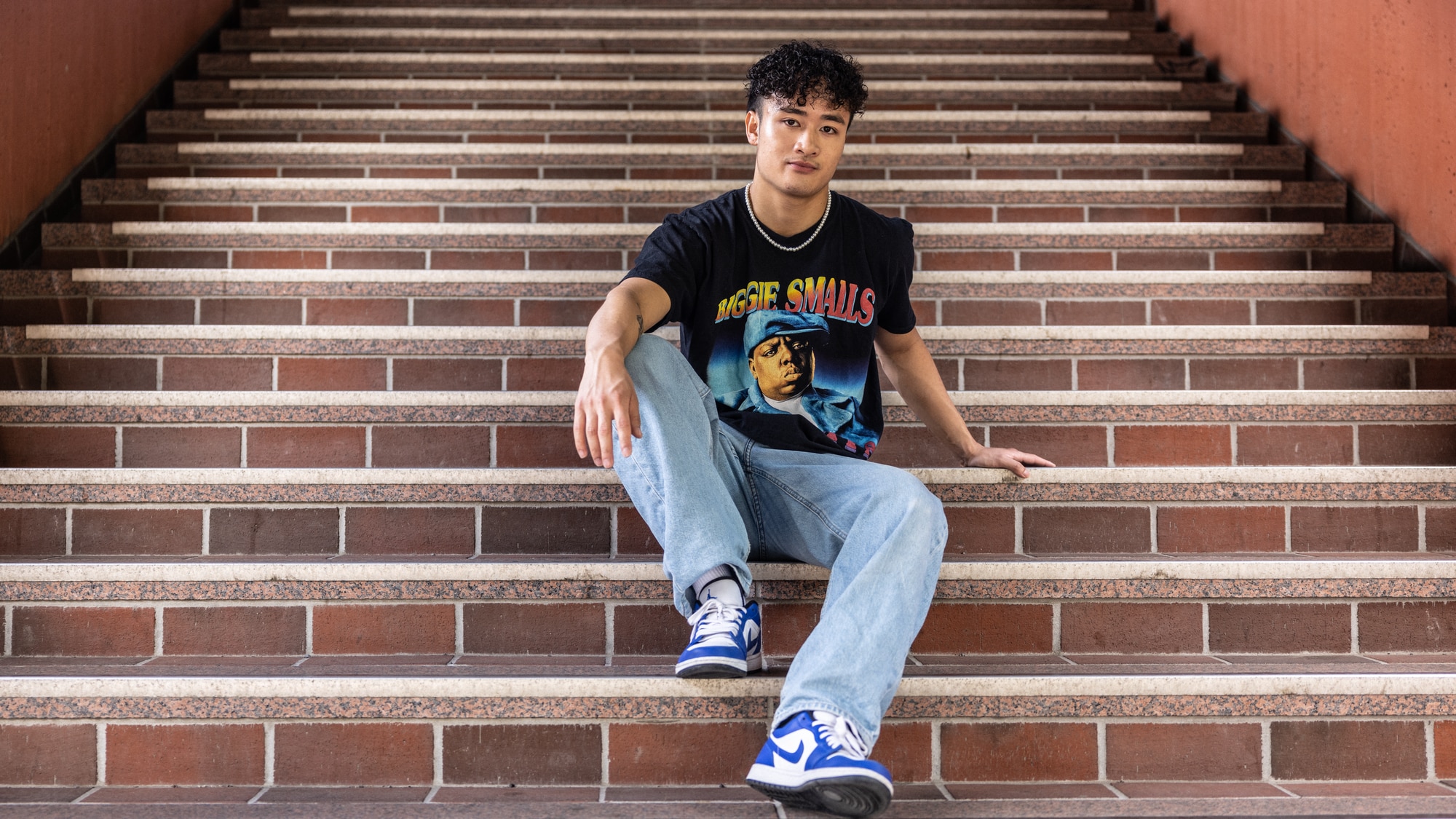 Bilde av Van Dan Nguyen (21) i en trapp på Holmlia togstasjon. Han har på seg blå Nike-sko, en jeans og en svart T-skjorte med bilde av rapperen The Notoriuos B.I.G.  