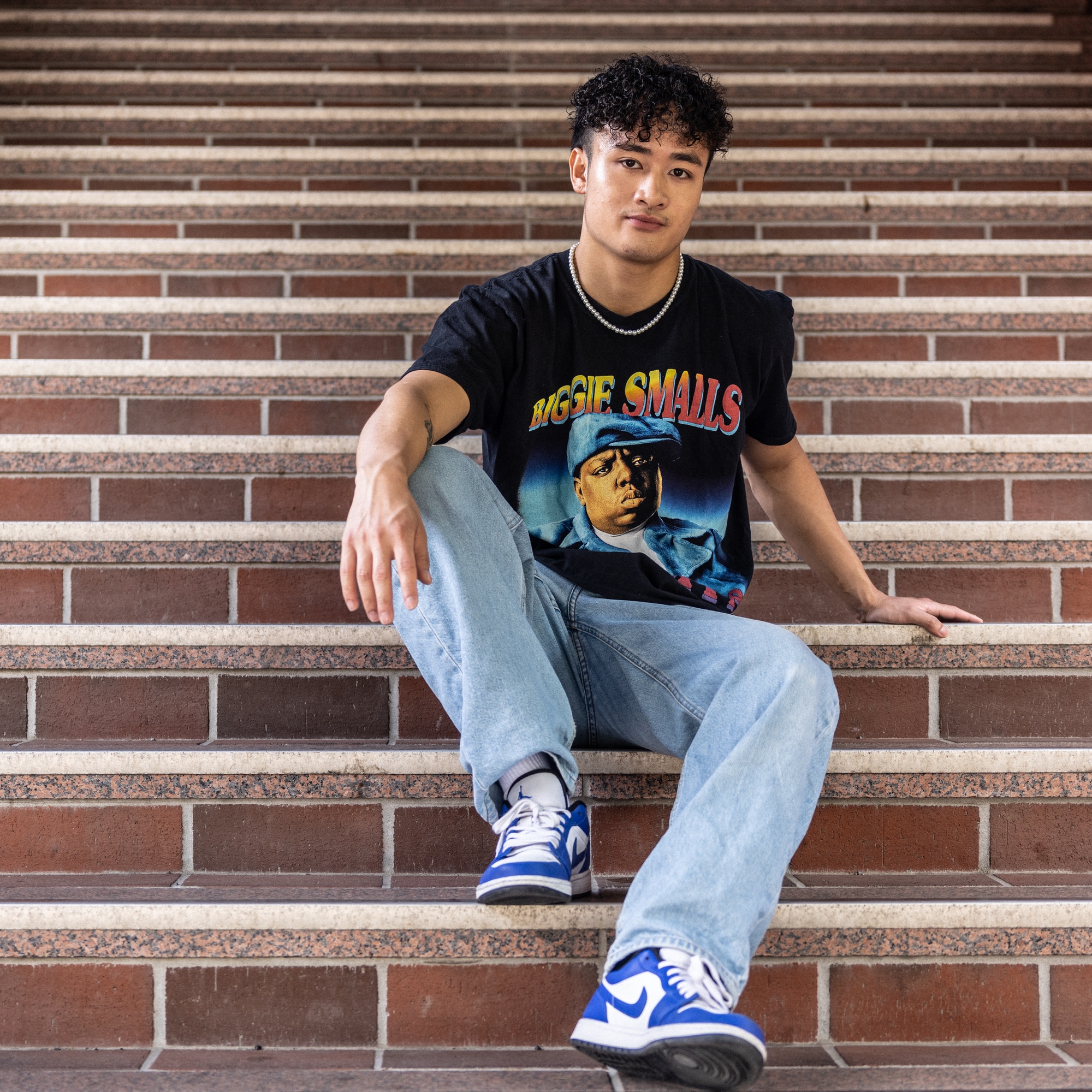 Bilde av Van Dan Nguyen (21) i en trapp på Holmlia togstasjon. Han har på seg blå Nike-sko, en jeans og en svart T-skjorte med bilde av rapperen The Notoriuos B.I.G.  