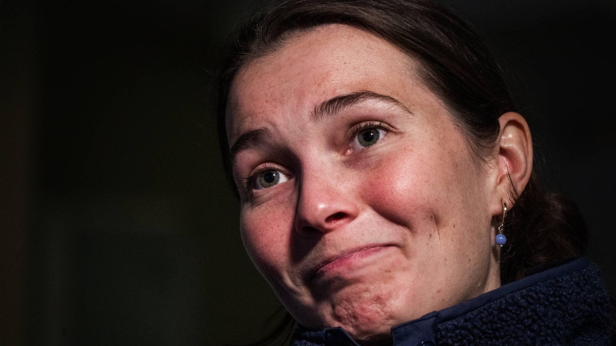 Nærbilde av en kvinne med mørkt hår, kledd i en mørk blå fleecegenser. (Bildebeskrivelsen er laget av en KI-tjeneste)
