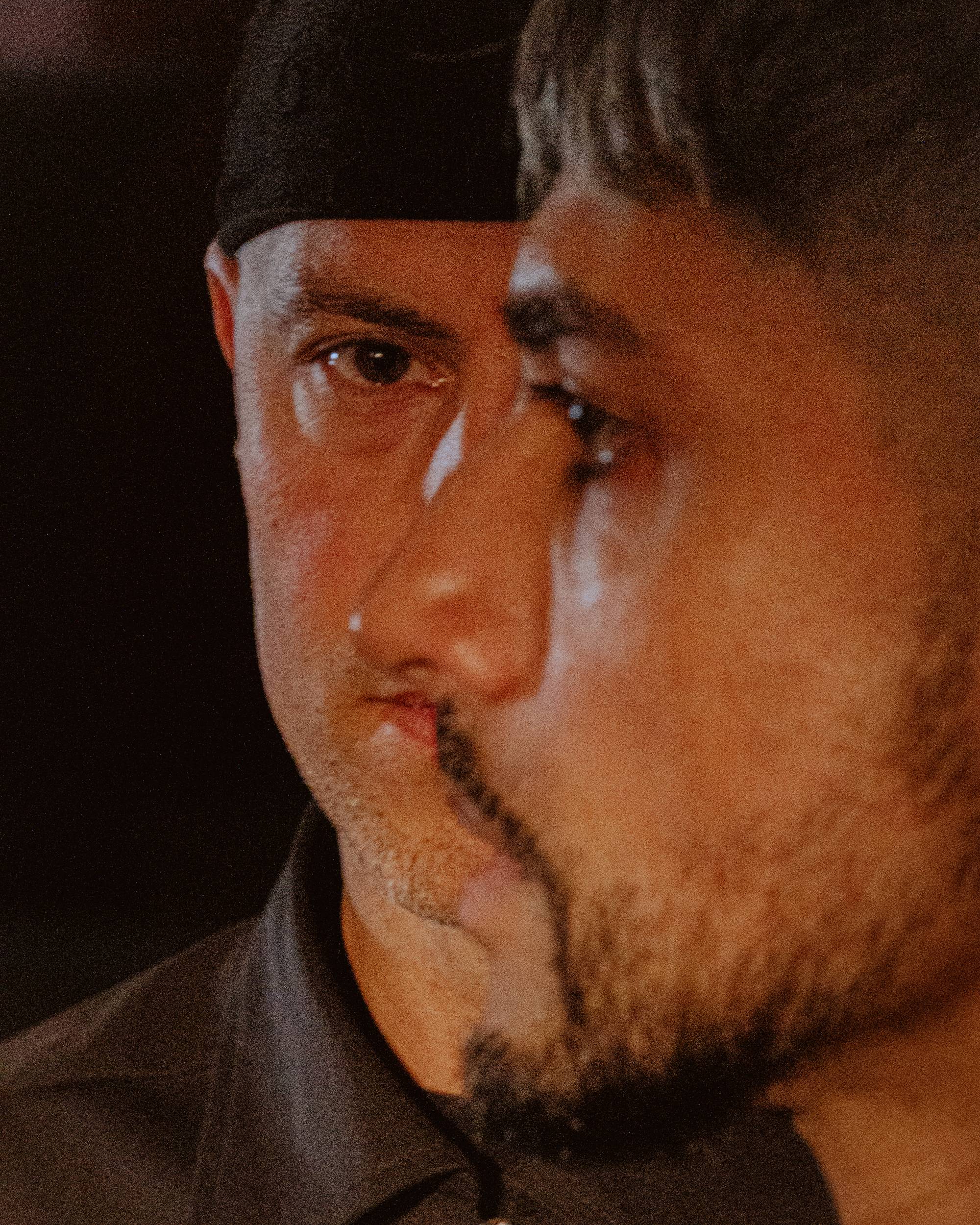 Magdi ser rett i kamera. Halve ansiktet fylles ut av ansiktet til Chirag sett i profil