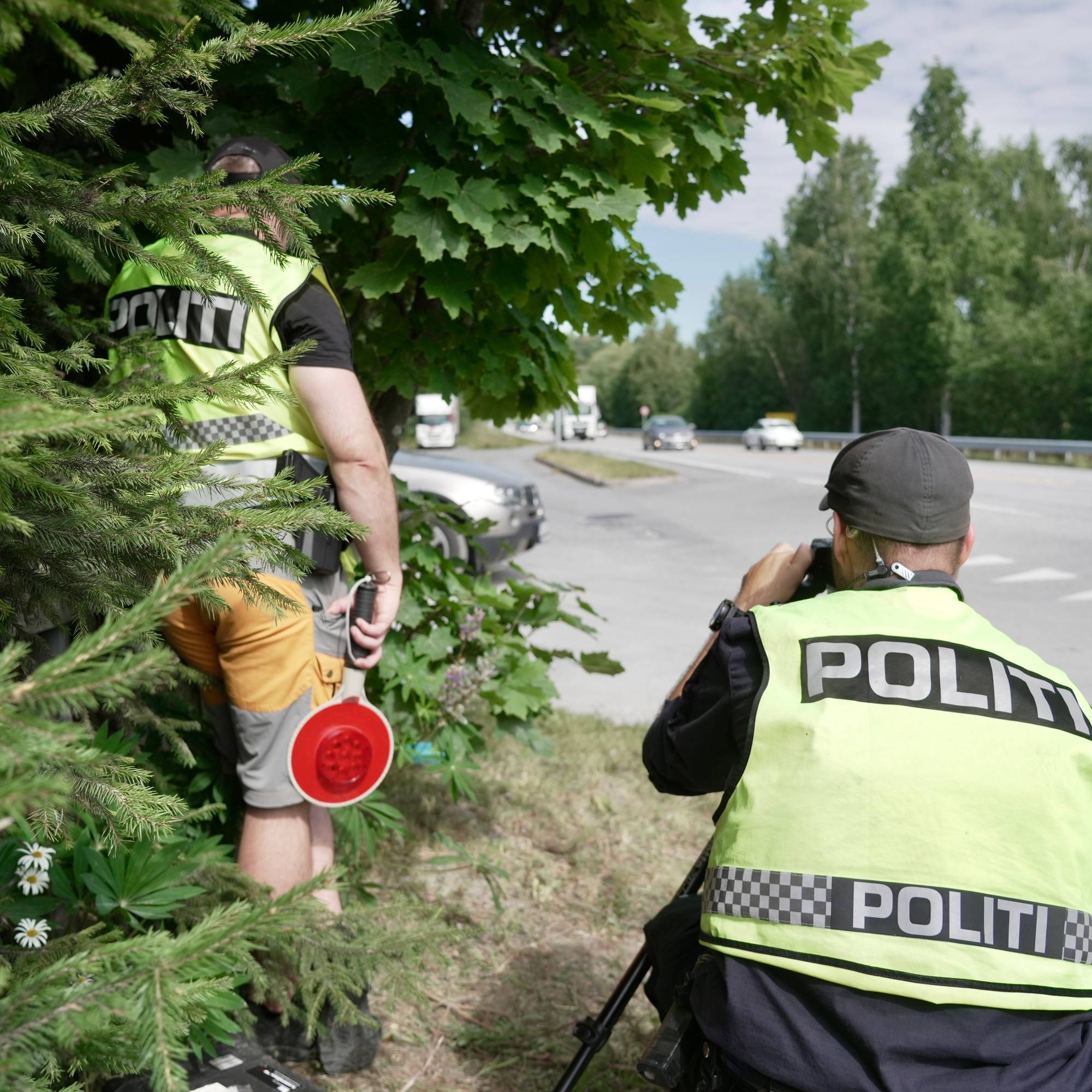 Politibetjenter utfører fartskontroll langs en vei. 