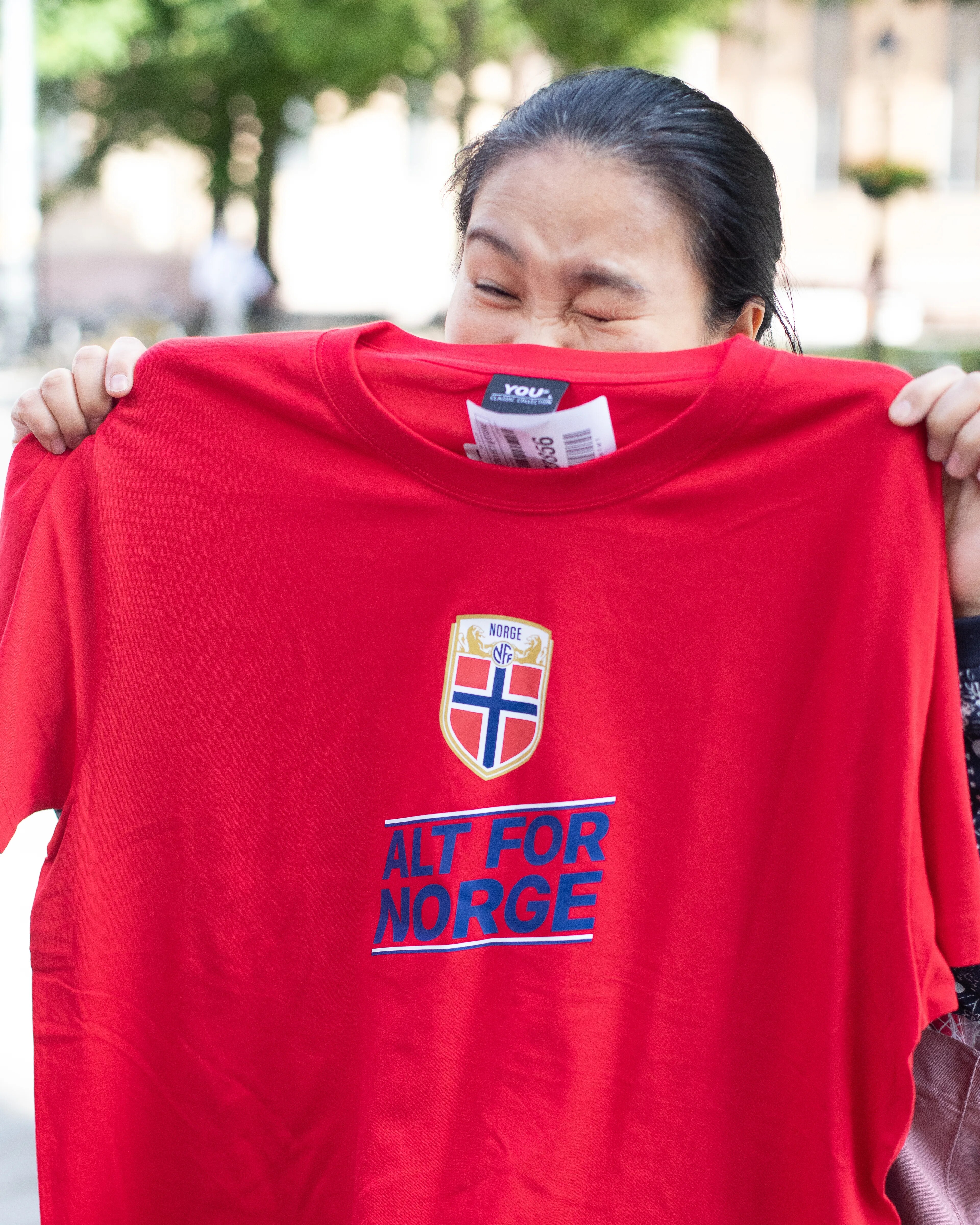 en kvinne viser frem en rød t-skjorte der det står alt for norge