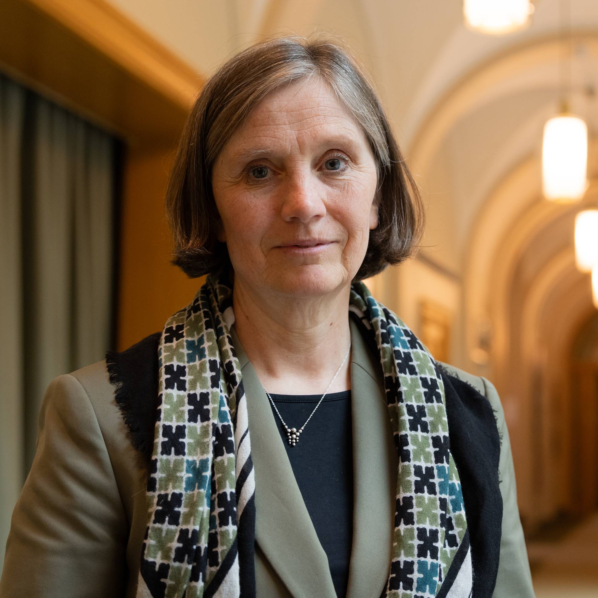 Kvinne med grått kort hår ser i kamera