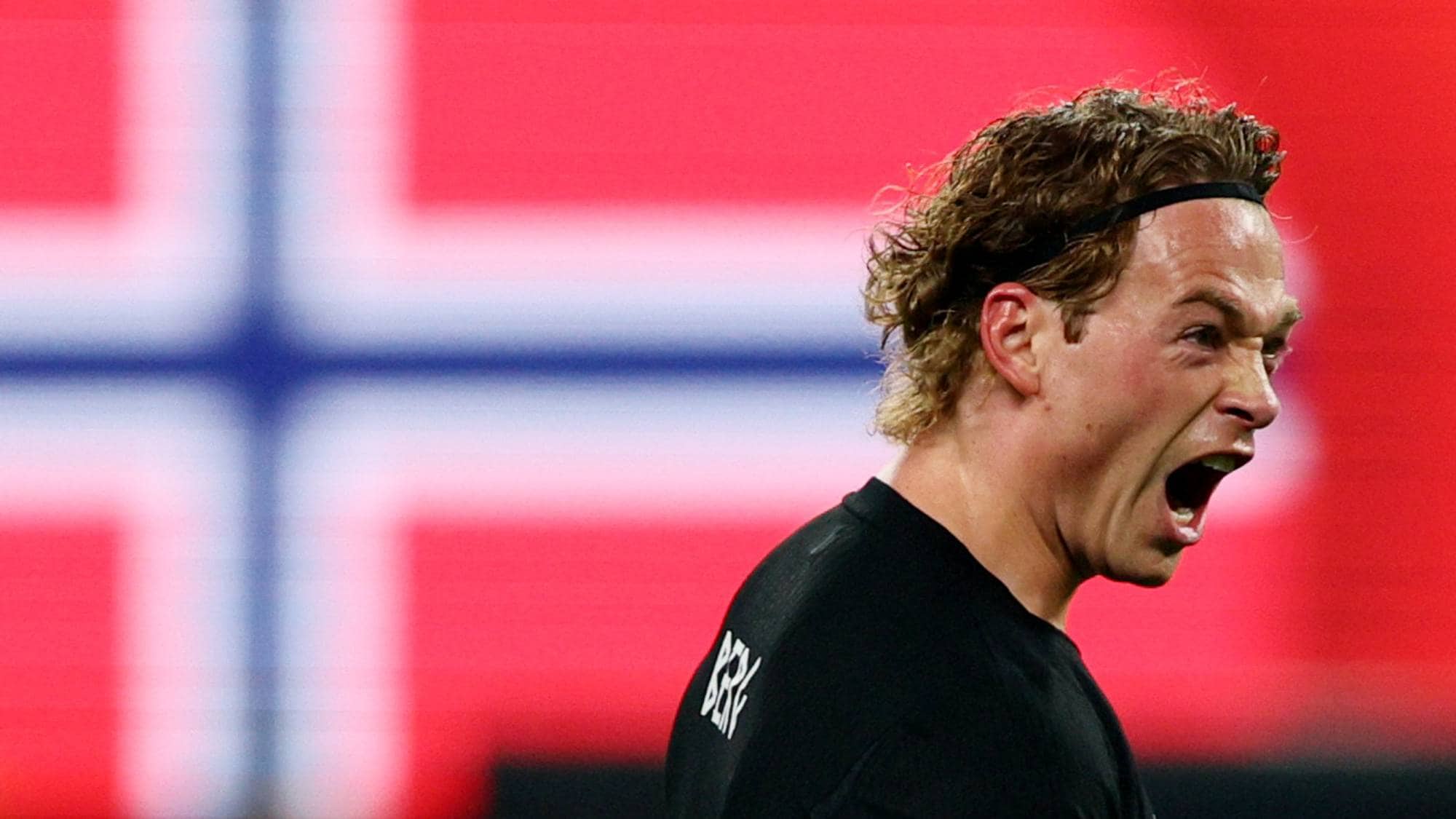 Fotballspilleren Patrick Berg roper med et norsk flagg i bakgrunnen. (Bildebeskrivelsen er laget av en KI-tjeneste)