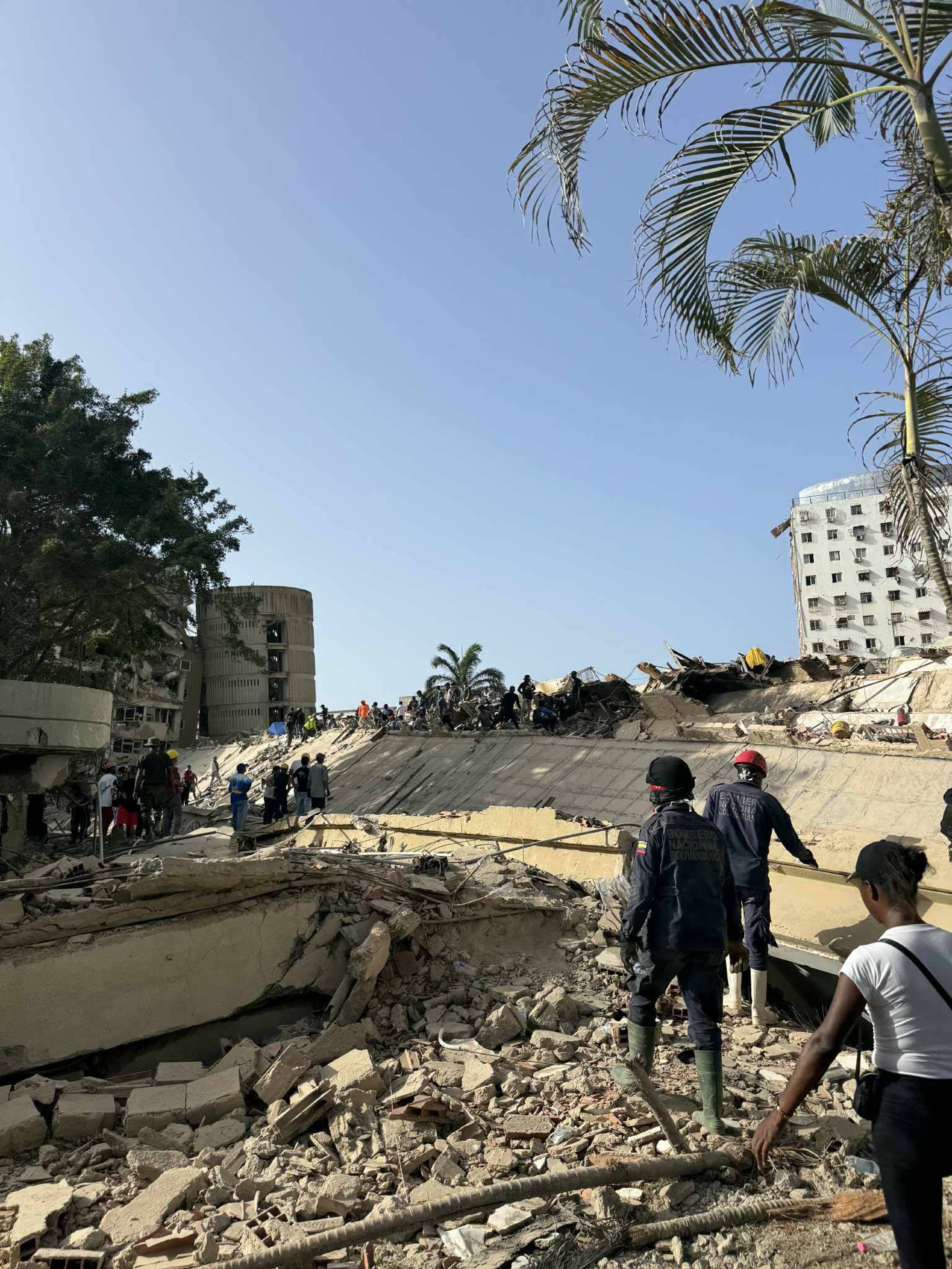 Redningspersonell og sivile ved et sammenrast bygg etter en eksplosjon i Santo Domingo. (Bildebeskrivelsen er laget av en KI-tjeneste)