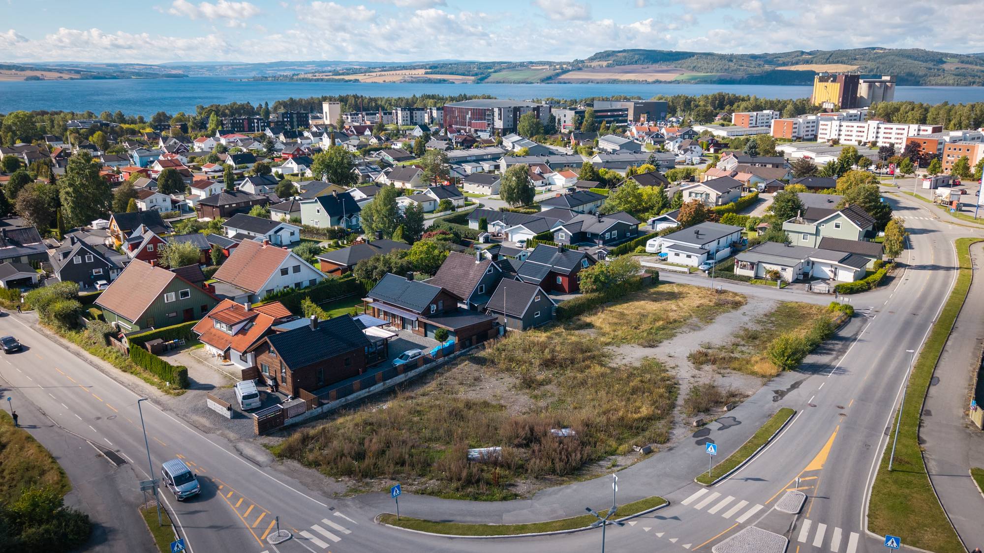 Boligtomt med mange hus i bakgrunnen i Hamar sett fra luften. Mjøsa i bakgrunnen 