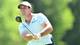 Foto: MINAS PANAGIOTAKIS / GETTY IMAGES NORTH AMERICA,NTB En golfspiller i lysblå polo og hvit caps slår et slag. Spilleren fokuserer på ballen mens han svinger golfkøllen. Bakgrunnen er uskarp grønn vegetasjon, noe som indikerer en utendørs bane. (Bildebeskrivelsen er laget av en KI-tjeneste)