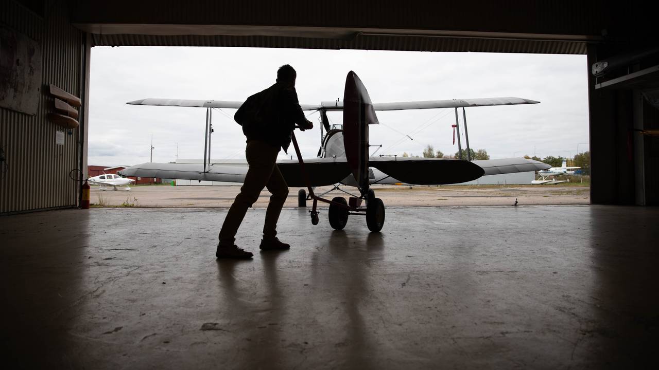 Finn Terje Skyrud skyver et gammelt fly ut av hangaren på Kjeller flyplass.