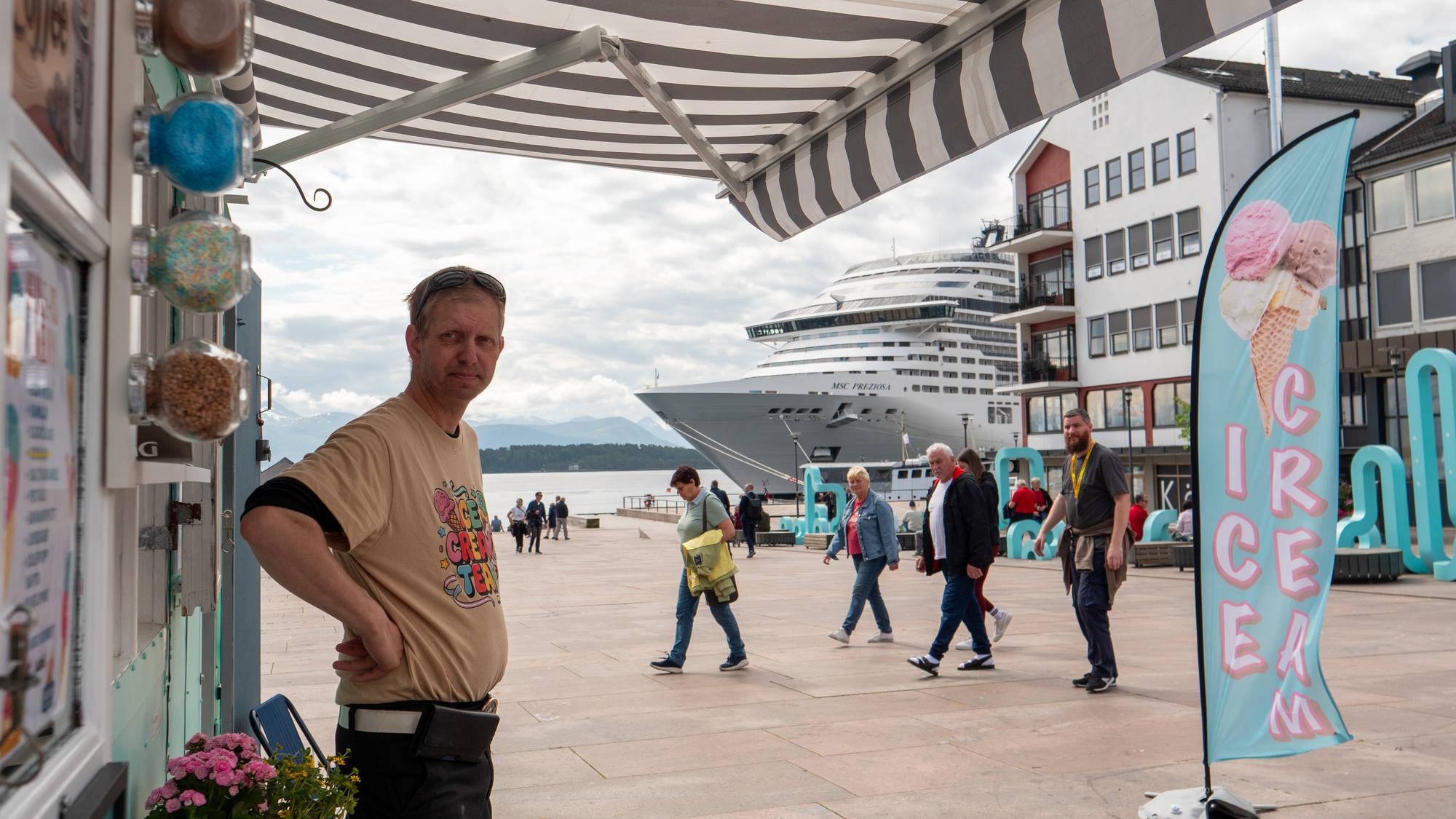 Knut Ivar Kvennes Pettersen framfor iskiosken på Molde-torget, stor cruisebåt i bakgrunn