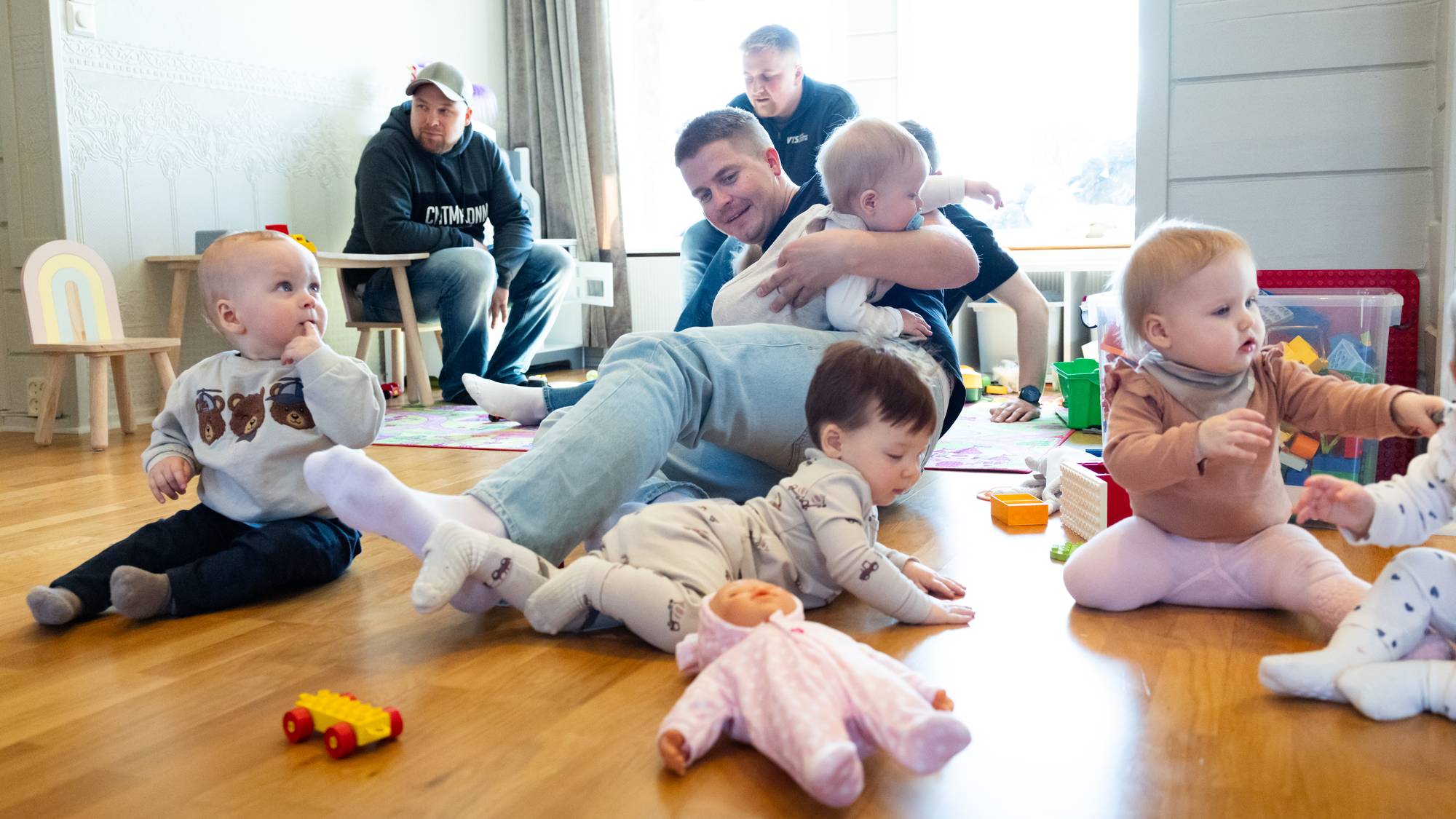 Pappa omgitt av små barn som leker på gulvet