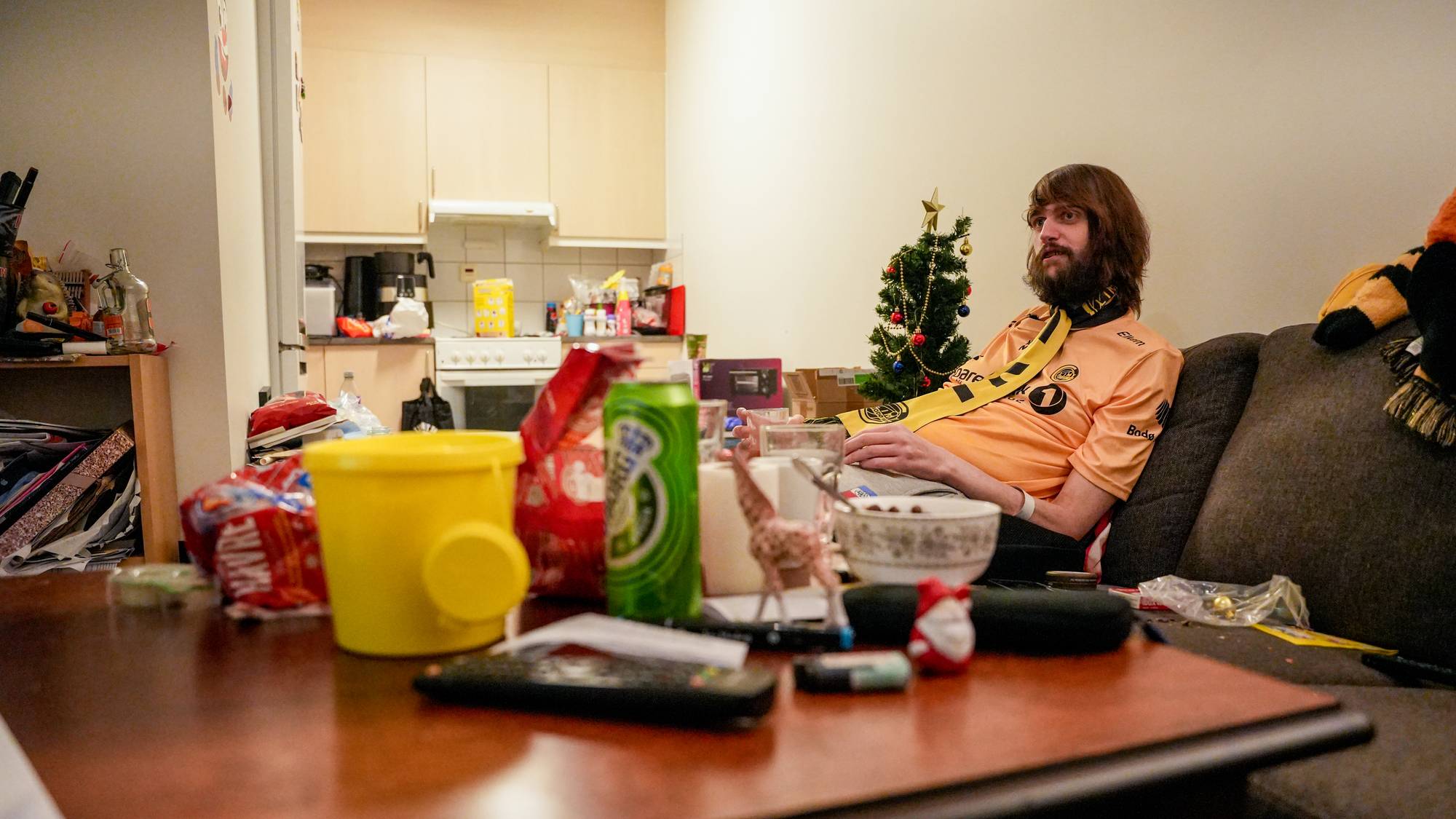 Eirik Finstad sitter i leiligheten sin. Foran han er et bord med en del rot. 