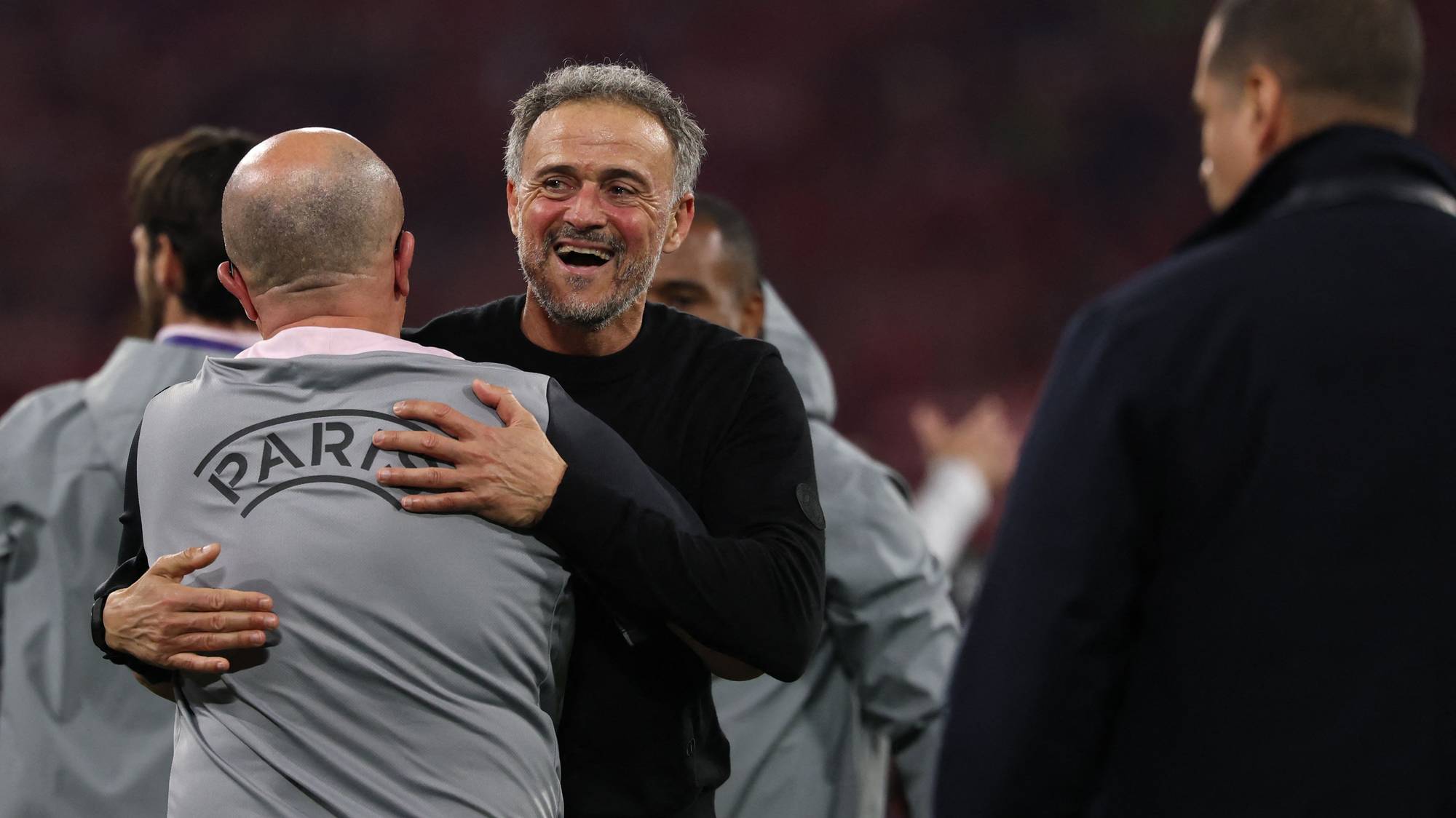 Luis Enrique omfavner en person på idrettsbane. En annen person står bak dem. (Bildebeskrivelsen er laget av en KI-tjeneste)