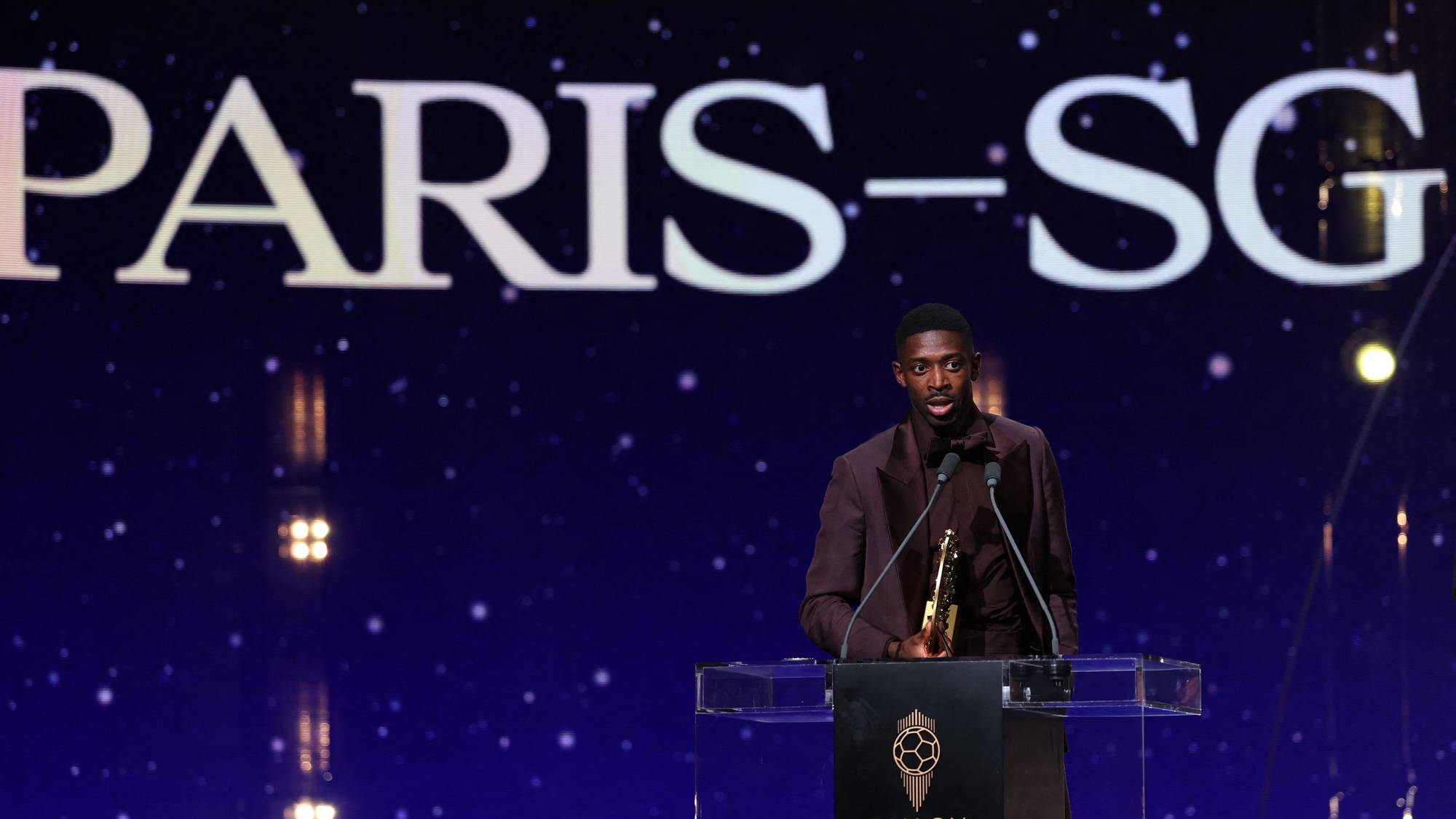 Ousmane Dembele ved en Ballon d'Or-utdeling foran en skjerm med teksten Paris-SG. (Bildebeskrivelsen er laget av en KI-tjeneste)