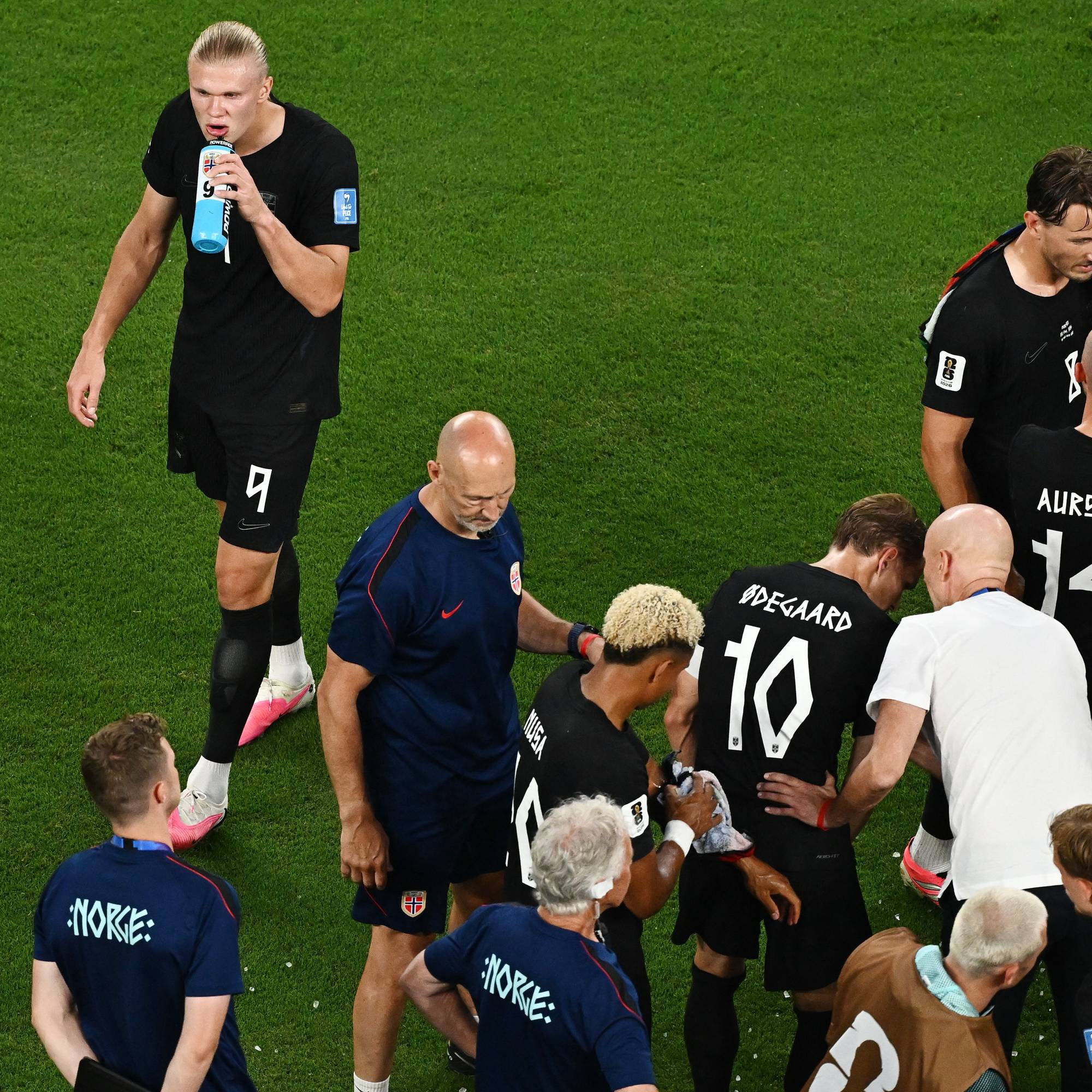 Norske fotballspillere og støtteapparat samlet på gressmatten etter kamp. (Bildebeskrivelsen er laget av en KI-tjeneste)
