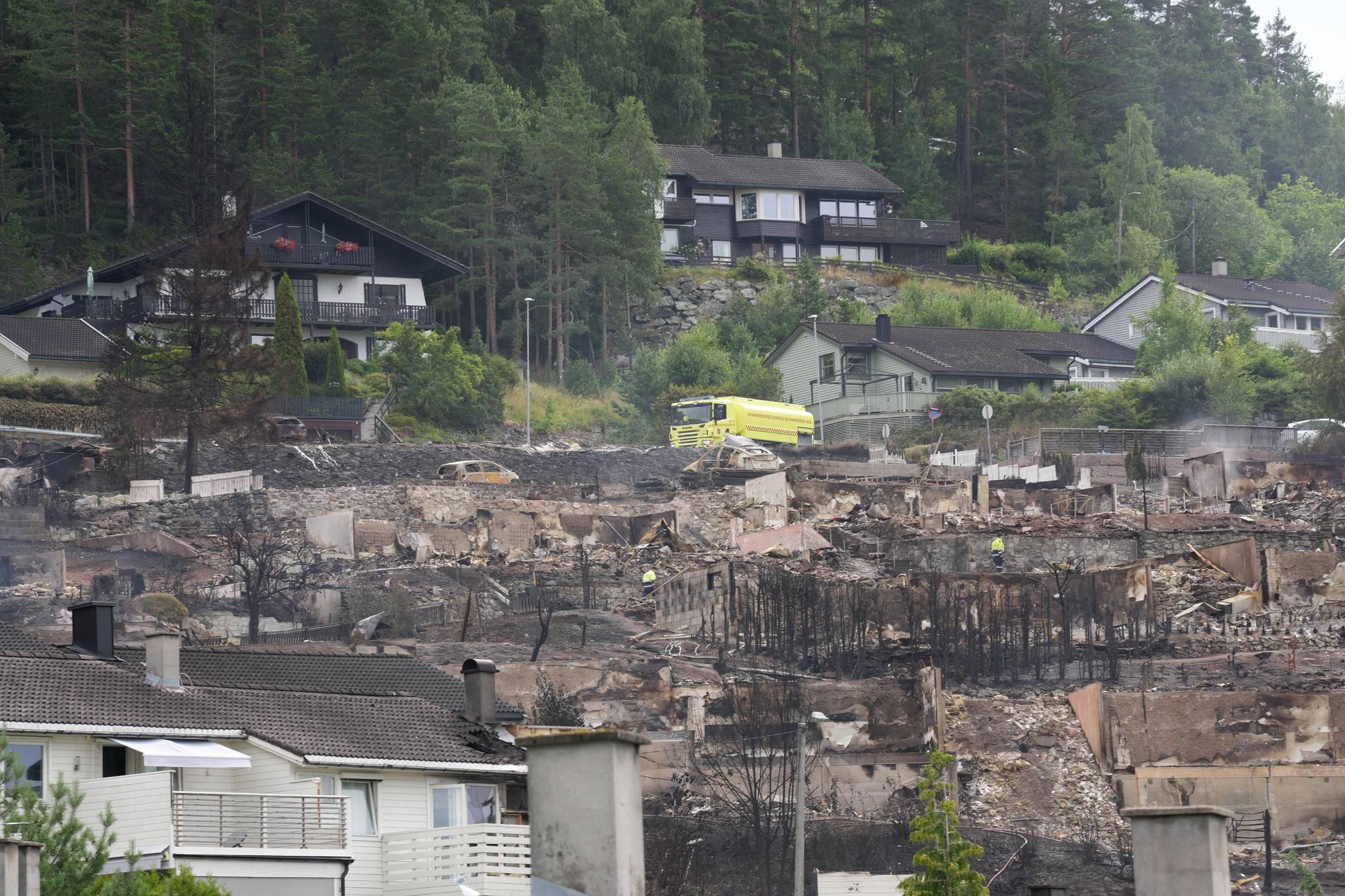 Flere nedbrente bygninger med en brannbil i midten. 