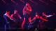 AFP En kvinnelig artist synger på en scene, mens fire mannlige dansere utfører en koreografi rundt henne. Artistens antrekk består av en glitrende topp, en kort skjørt og høye røde støvletter. Danserne er kledd i svarte, tettsittende klær og solbriller. Bak artisten lyser en bakgrunn med røde linjer. Scenen er opplyst i sterke, dramatiske farger. (Bildebeskrivelsen er laget av en KI-tjeneste)