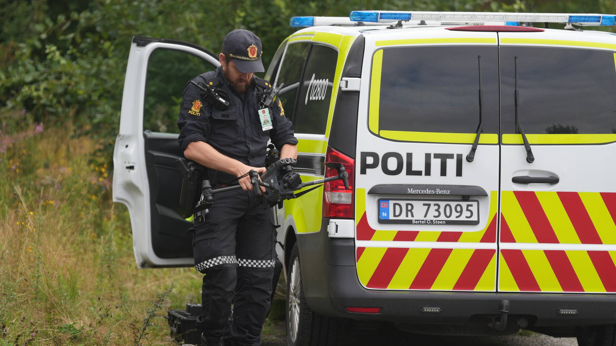 en politimann som står ved siden av en politibil