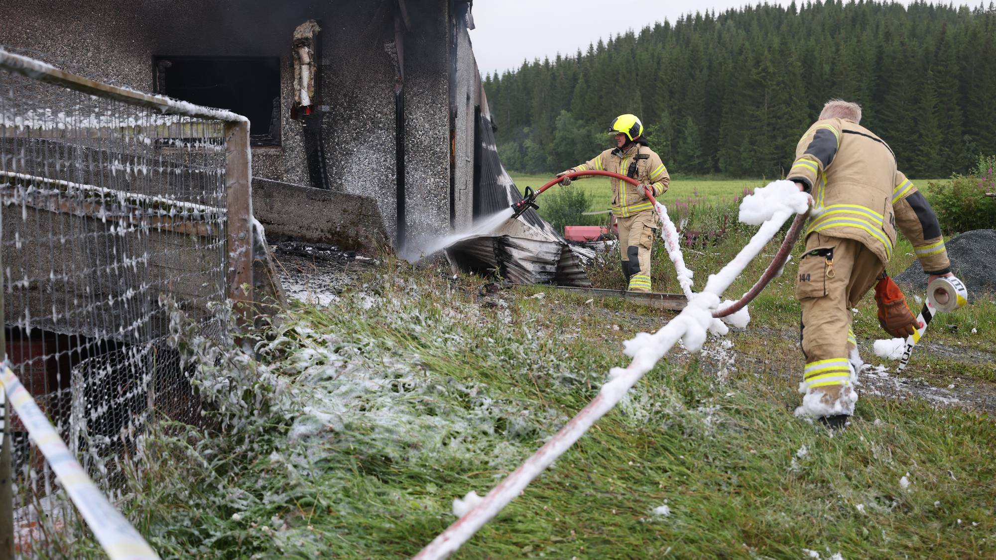 To brannkonstabler driver med etterslukking av en låvebrann