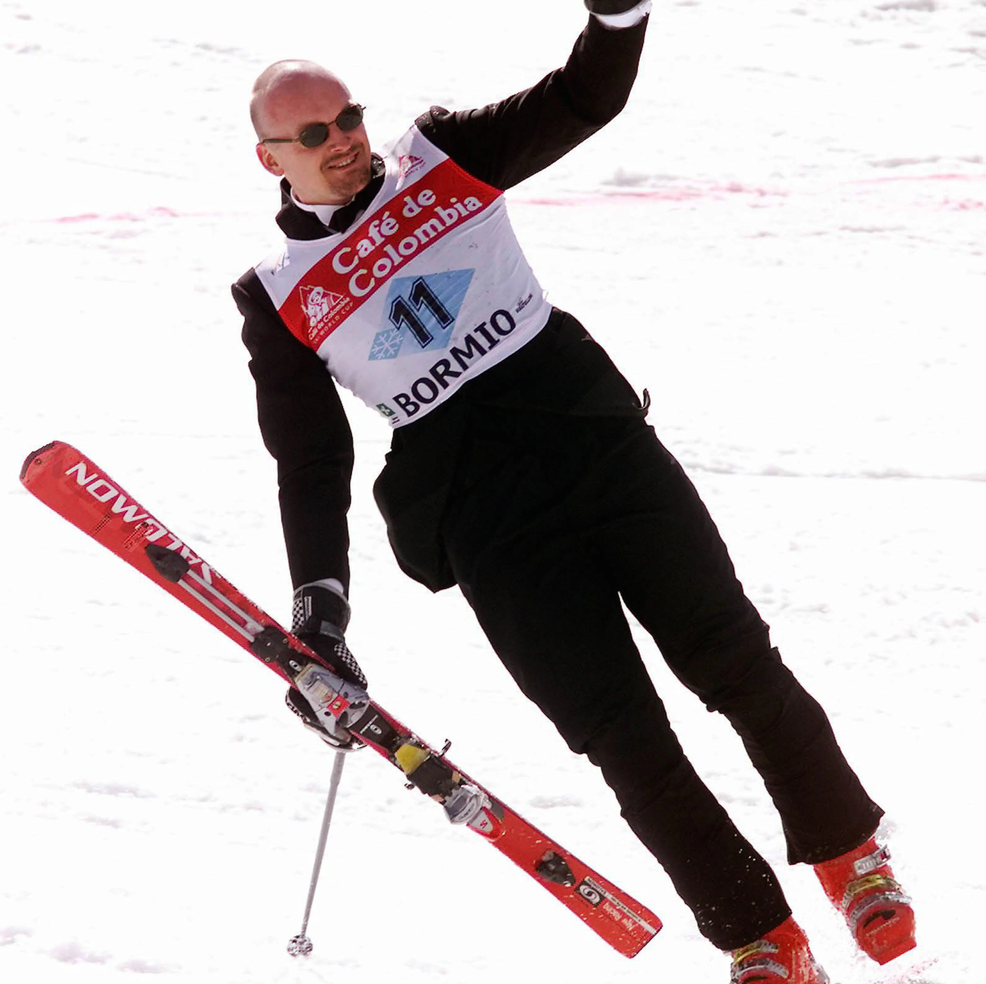 Alpinist kjører ned en snødekket bakke med n arm hevet i Bormio. (Bildebeskrivelsen er laget av en KI-tjeneste)