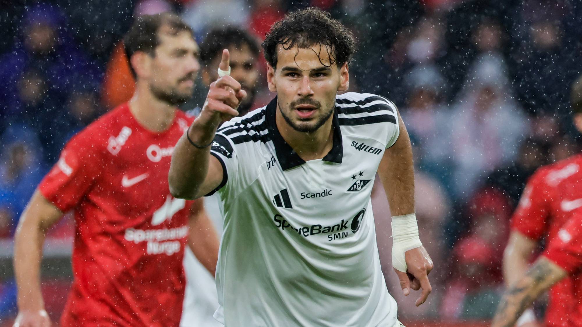Rosenborg-spiller jubler med hevet finger under en fotballkamp i regnvær. (Bildebeskrivelsen er laget av en KI-tjeneste)