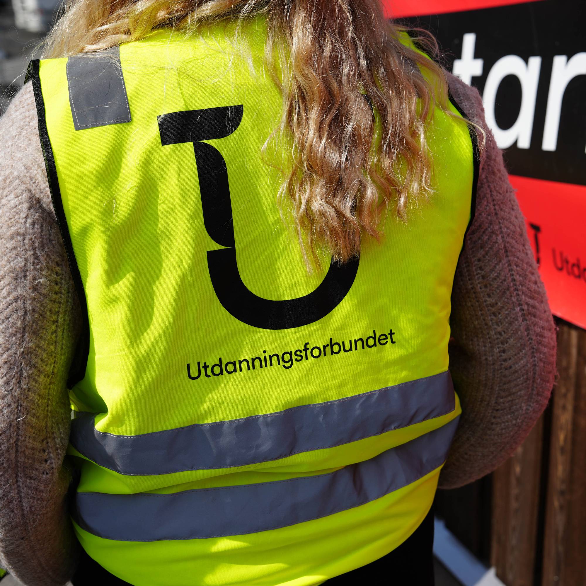 Biletet viser ryggen til ein streikande ved BKG. Ho har på seg ein refleksvest med logoen til Utdanningsforbundet. 