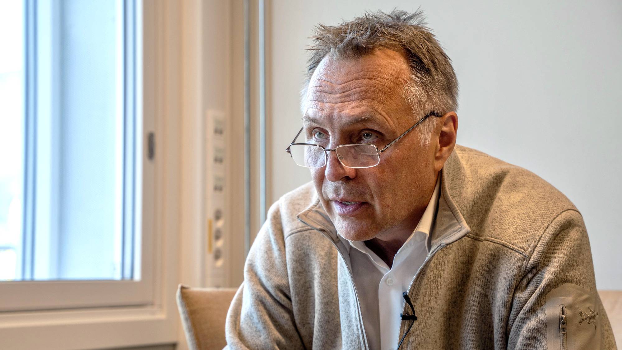 En mann med briller ser rett frem. Lys fra et vindu kommer inn fra siden. 