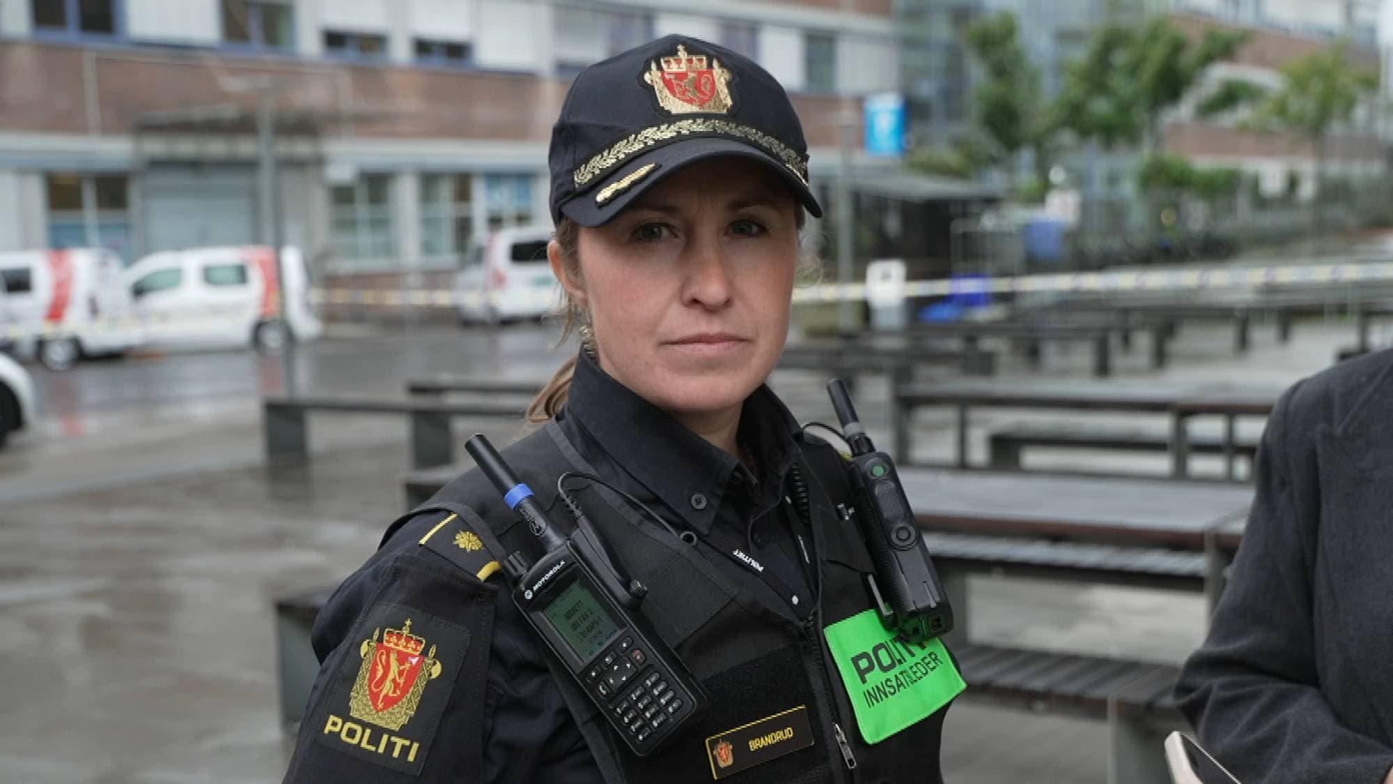 Politioverbetjent i uniform snakker med journalister utendørs. (Bildebeskrivelsen er laget av en KI-tjeneste)