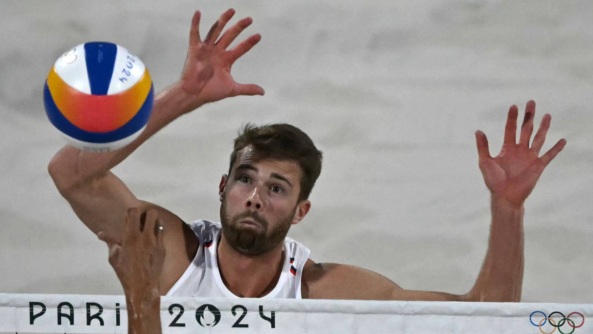 Sandvolleyballspiller for Norge blokkerer ballen over nettet under OL i Paris 2024. (Bildebeskrivelsen er laget av en KI-tjeneste)