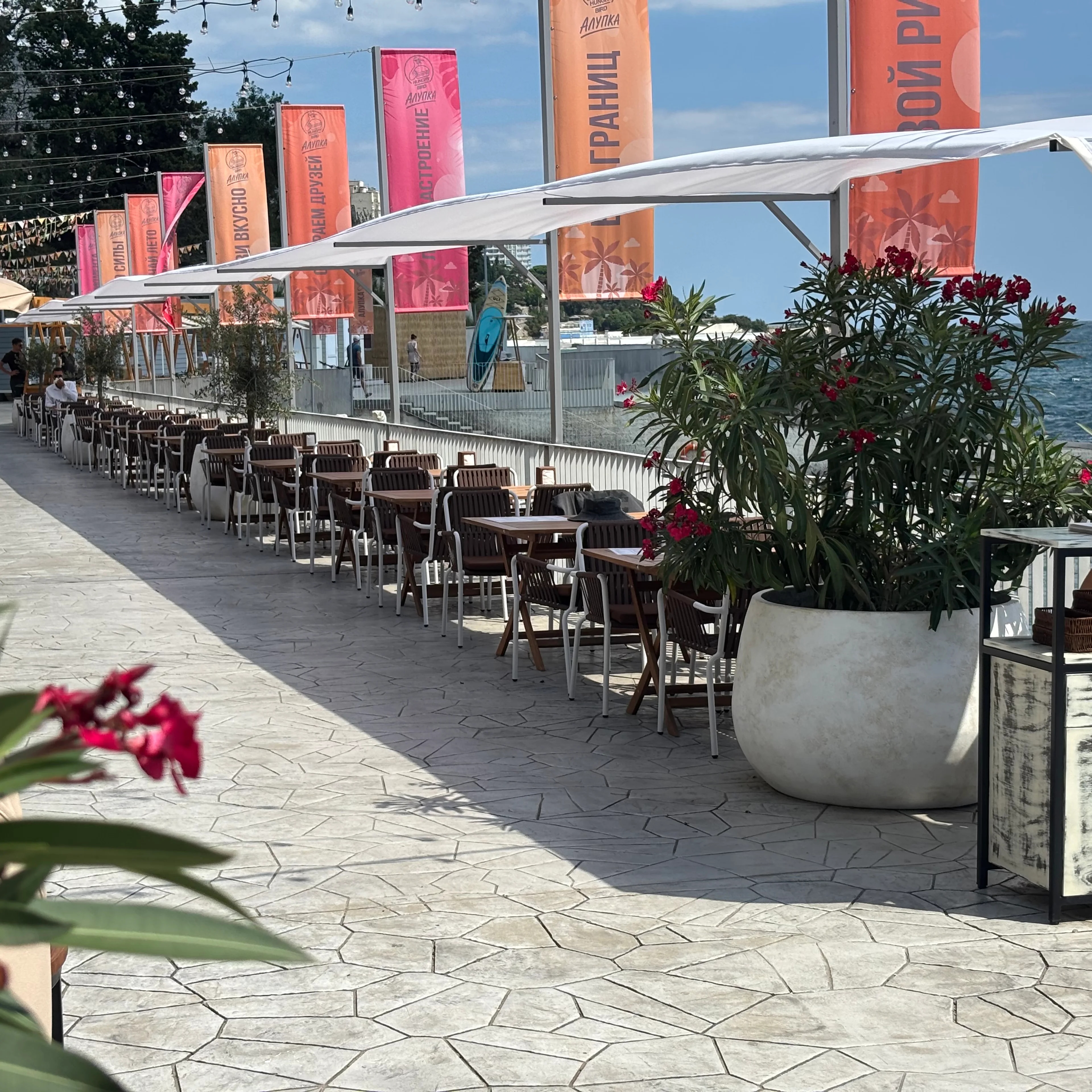 tomme bord og stoler på en restaurant med utsikt ut over havet.