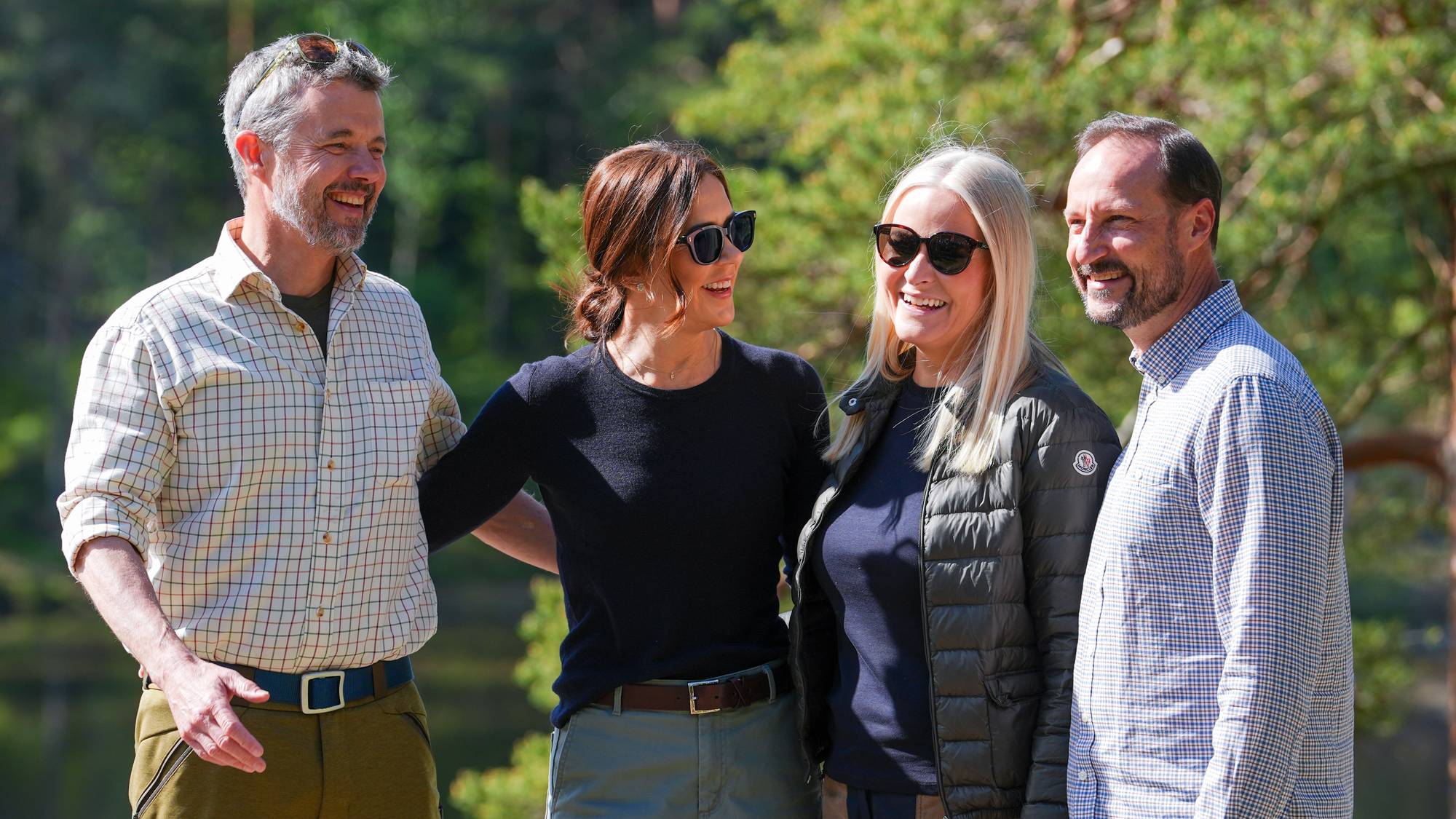 Kong Frederik, dronning Mary, kronprins Haakon og kronprinsesse Mette-Marit holder rundt hverandre og smiler mens de fotograferes ved Ulsrudvannet i Oslo
