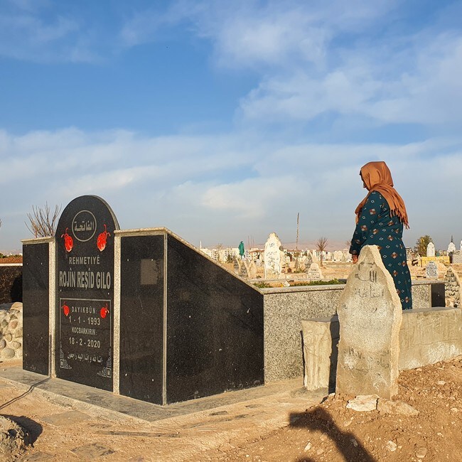 En kvinne i Syria står ved graven til en kvinne født i 1993, død 2020.