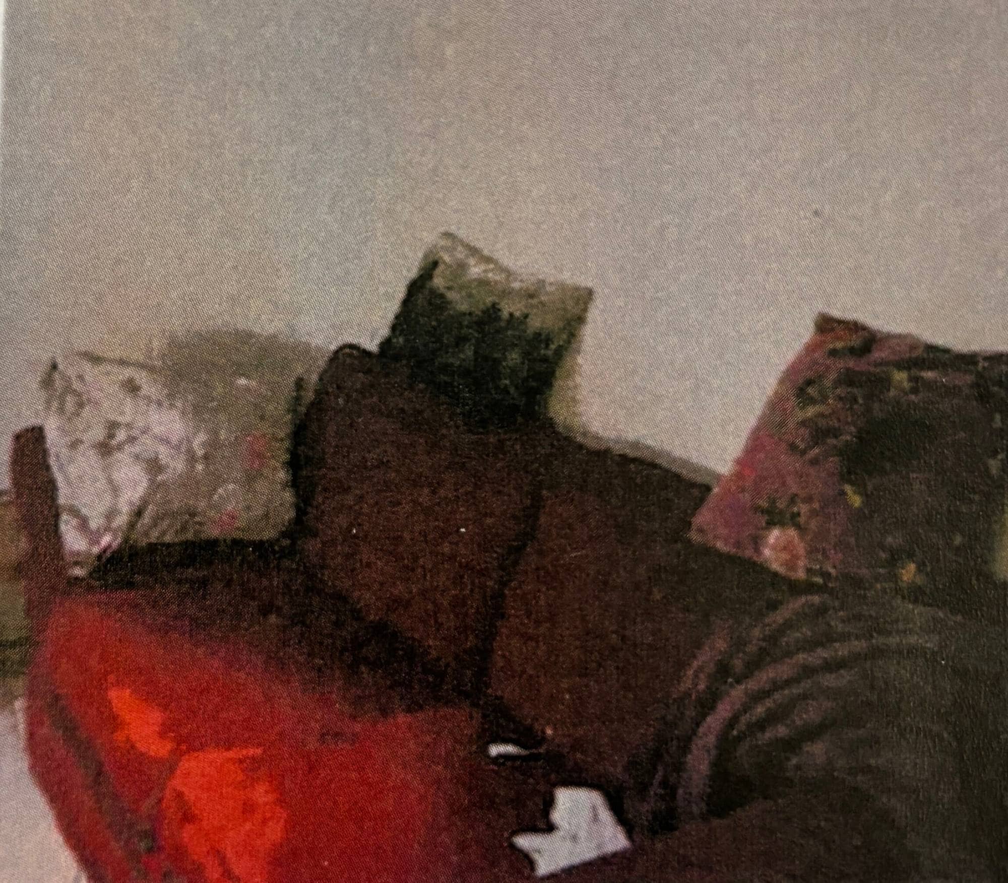 Et bilde med dårlig oppløsning som viser en rød sofa med tre puter.