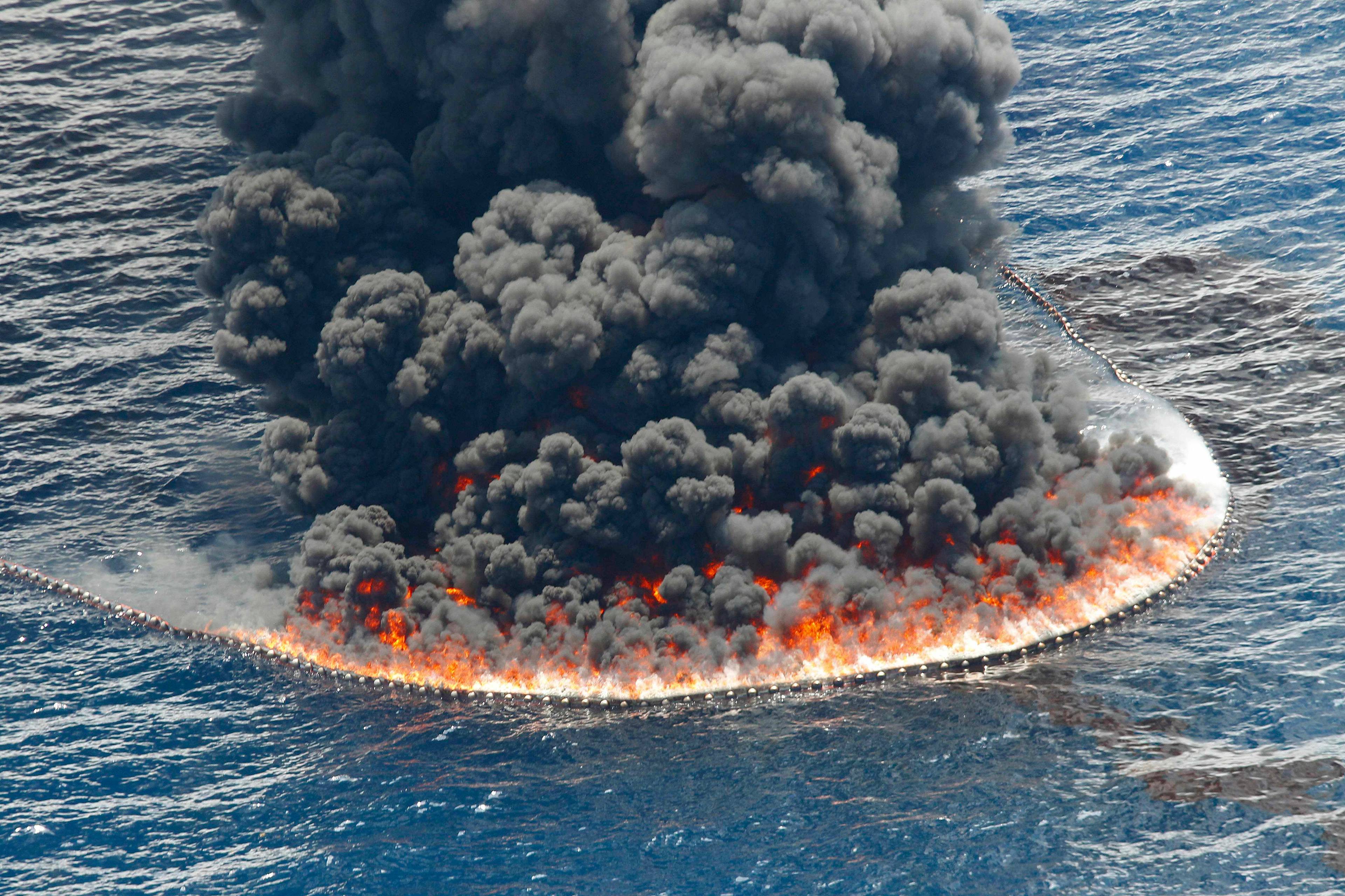 En kontrollert brann av råolje ute på sjøen nær stedet der Deepwater Horizon oljeriggen gikk ned. Mørk røyk stiger opp fra oljen som brenner.
