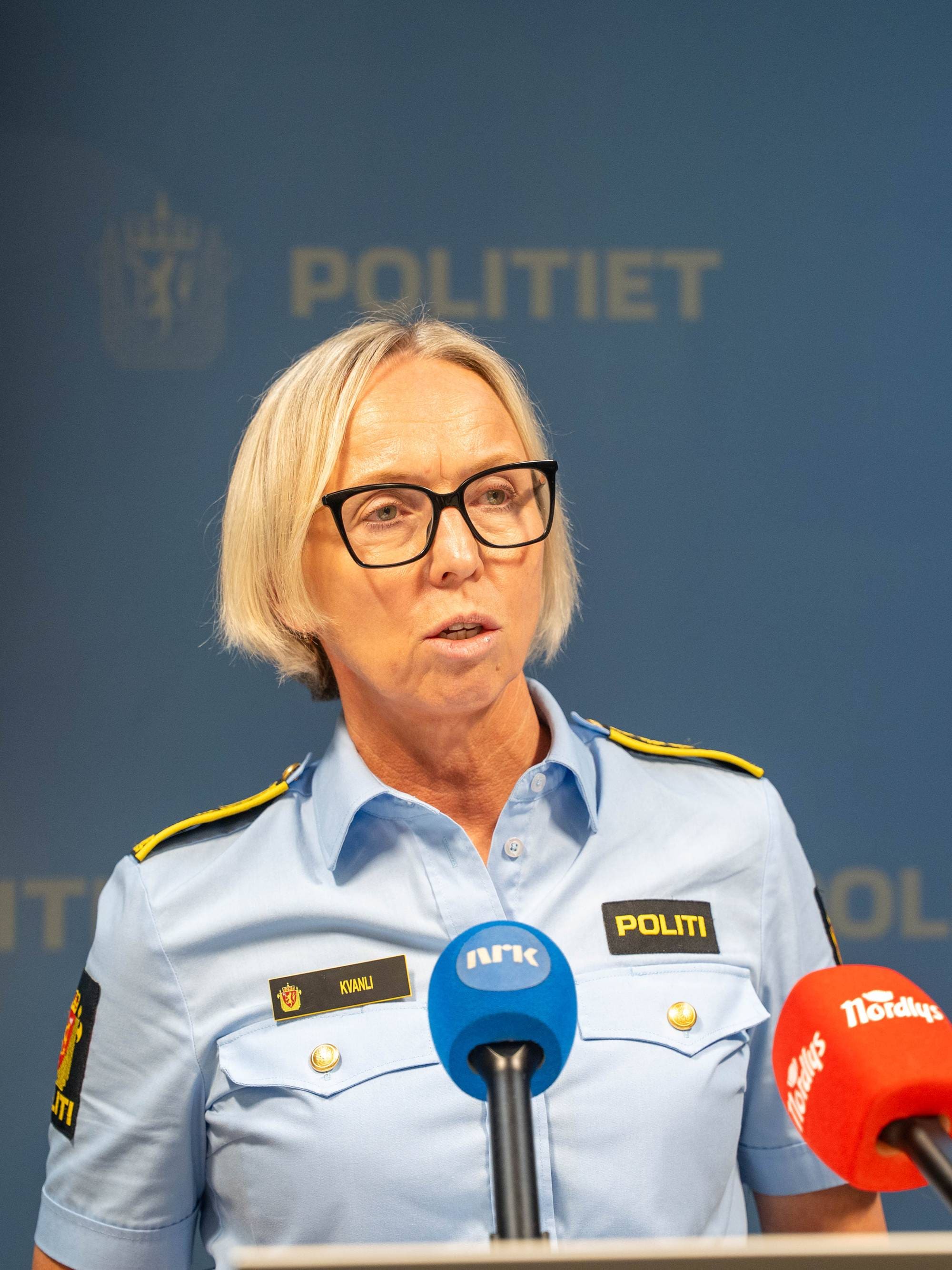 Politikvinne Kvanli holder pressekonferanse foran Politiet-logo. (Bildebeskrivelsen er laget av en KI-tjeneste)