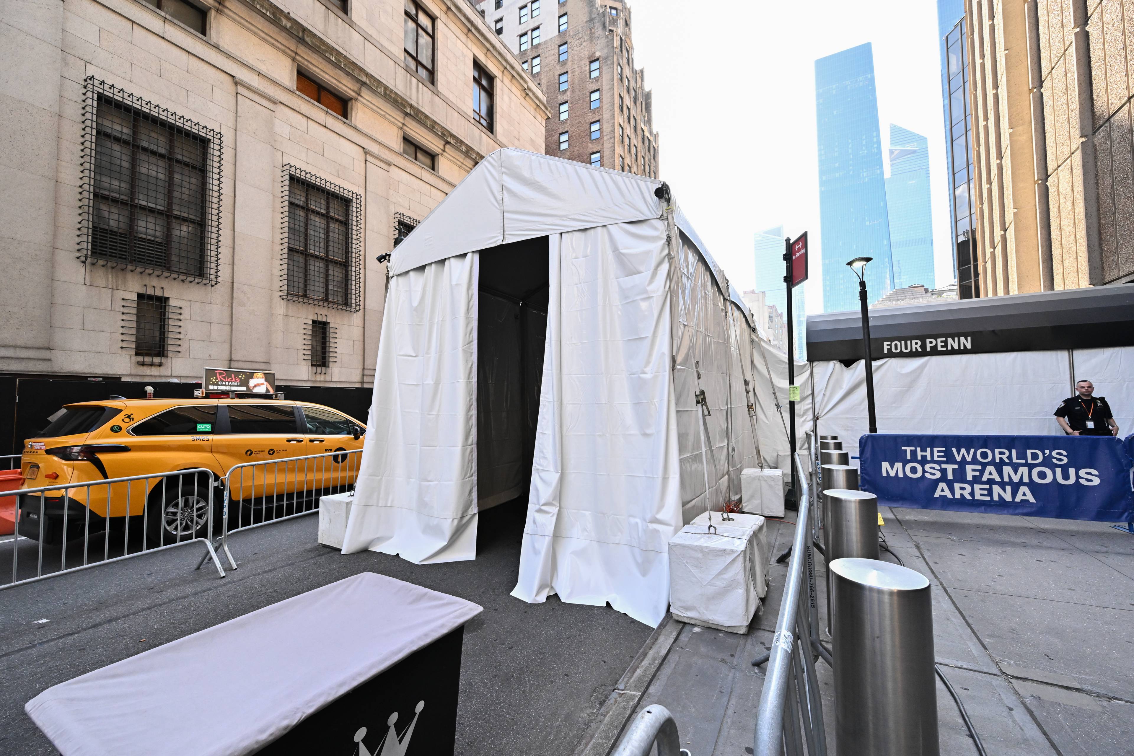 Hvitt telt oppstilt i en gate i New York ved Madison Square Garden. Gul taxi og vakt er synlige. (Bildebeskrivelsen er laget av en KI-tjeneste)