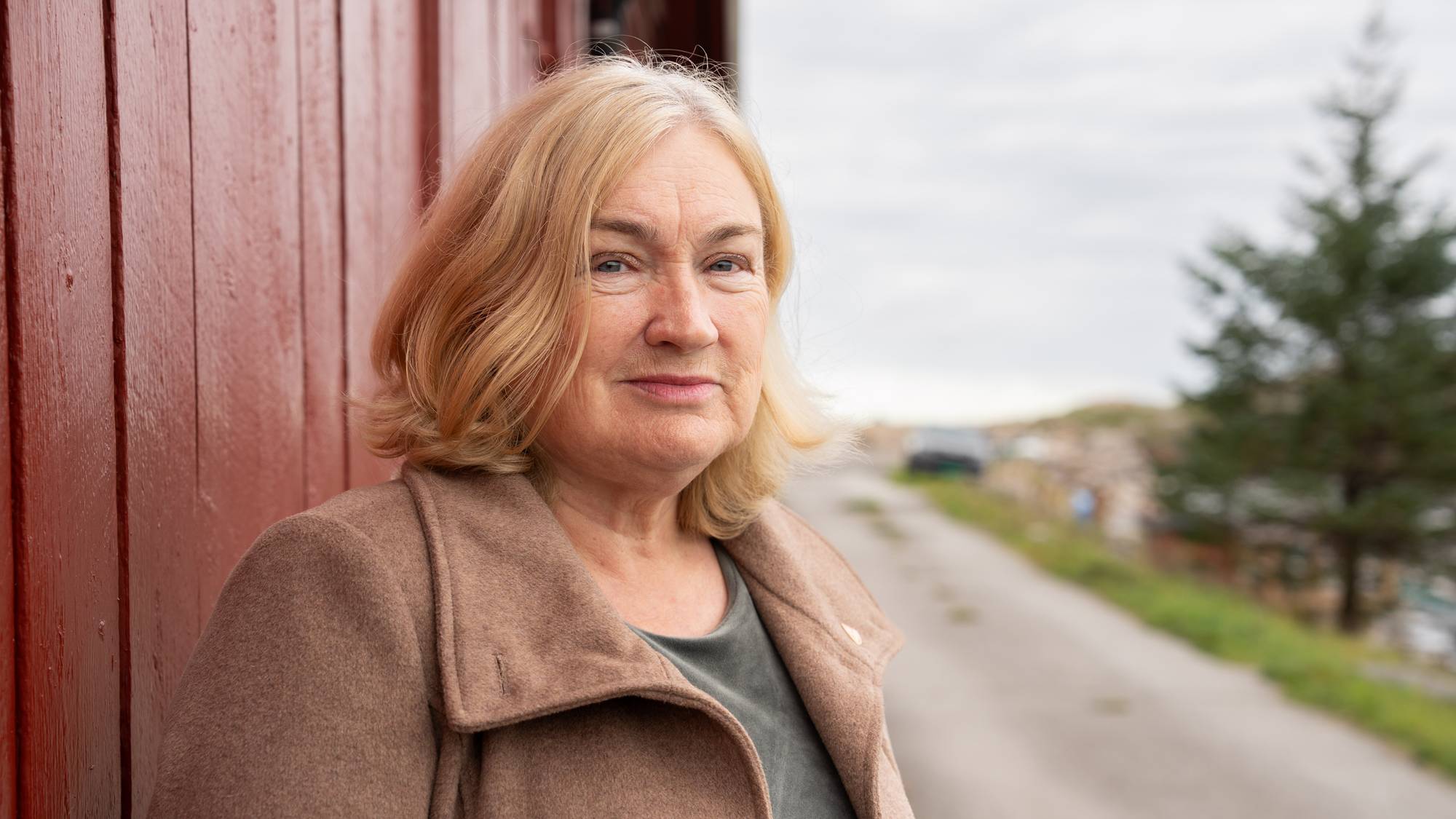 Ingrid Ovidie Rangønes står foran en rød bygning og smiler forsiktig til kamera.