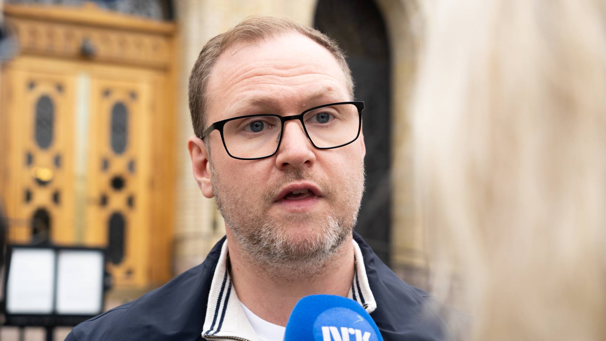 Erlend Svardal Bøe snakker til NRK i et intevju med Stortinget i bakgrunnen