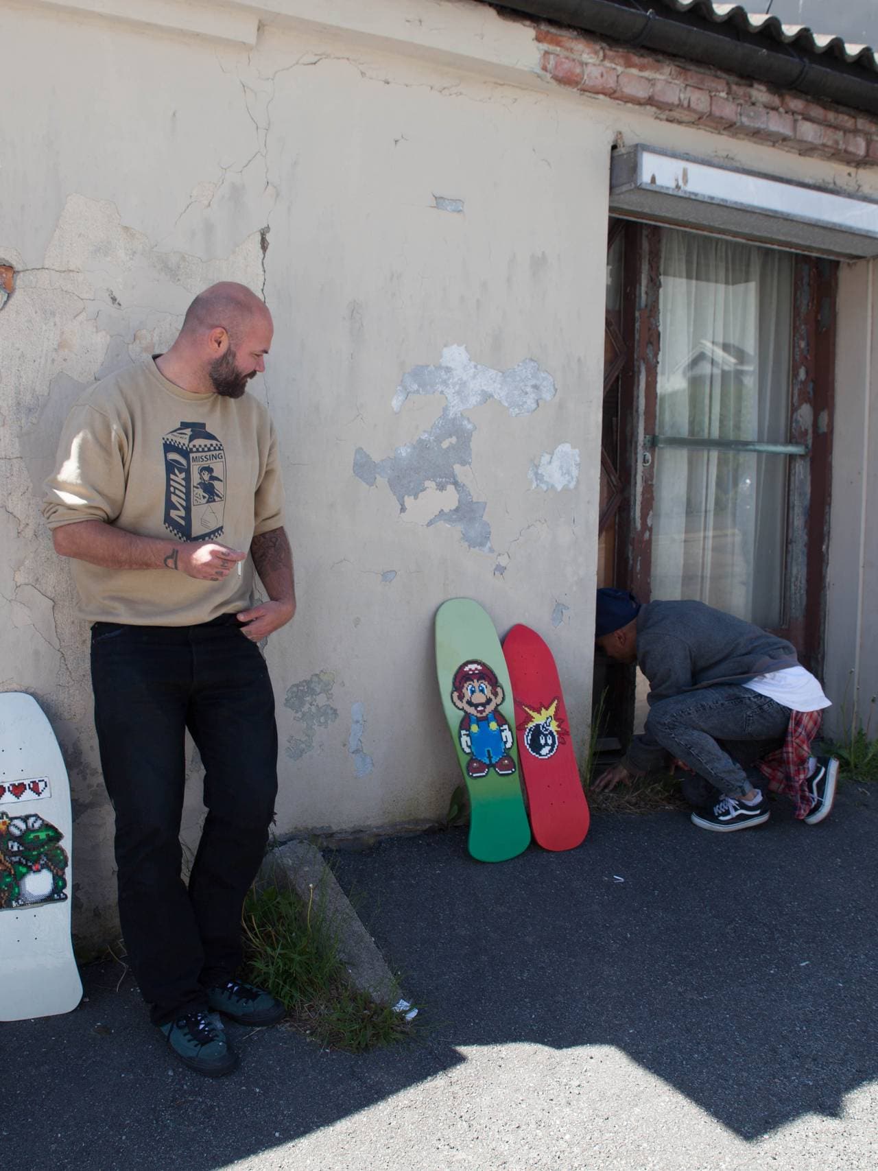 To karer foran en slitt bygård i LArvik med skateboardene de har laga