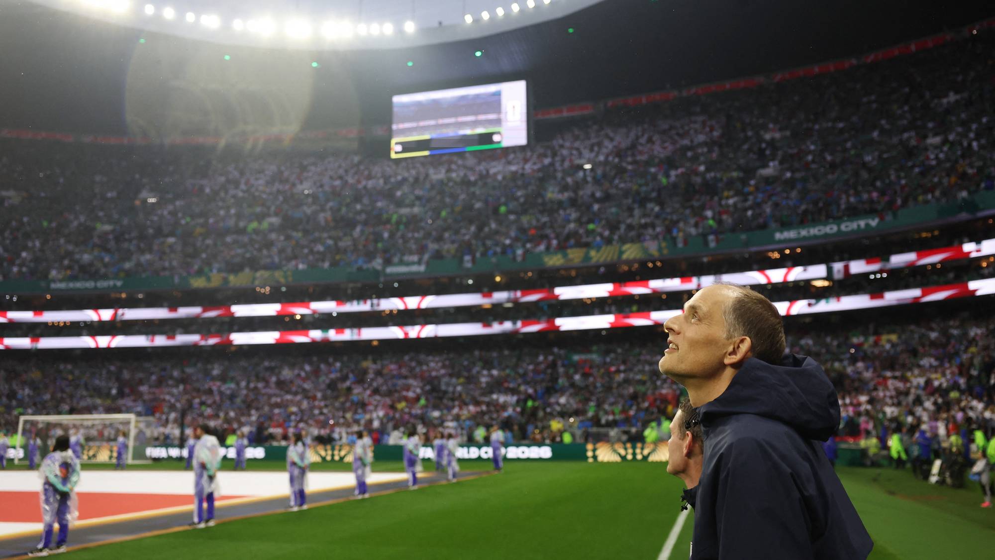 Thomas Tuchel ser opp mot en storskjerm på et fullsatt fotballstadion. (Bildebeskrivelsen er laget av en KI-tjeneste)
