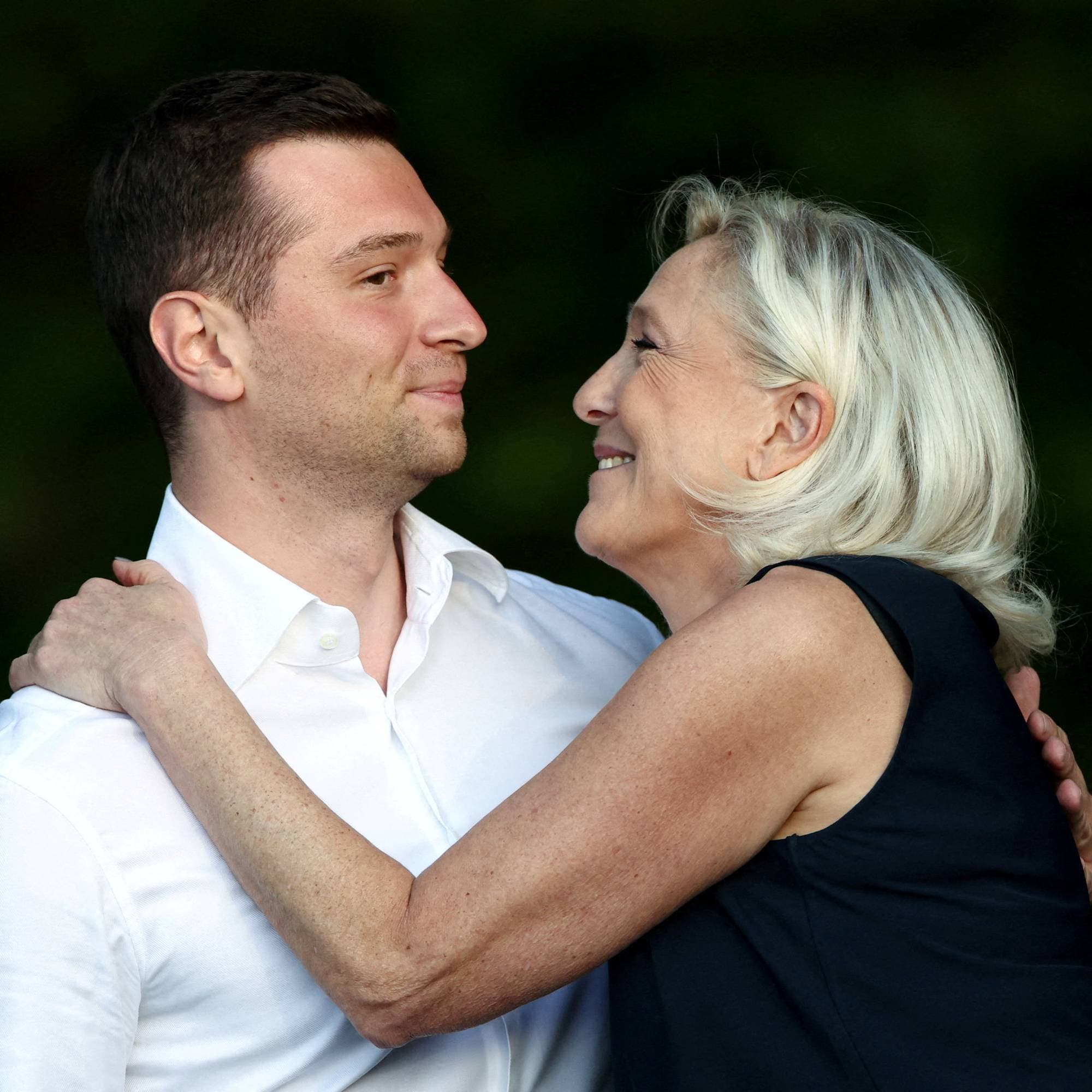 Marine Le Pen og Jordan Bardella i en nær samtale utendørs.