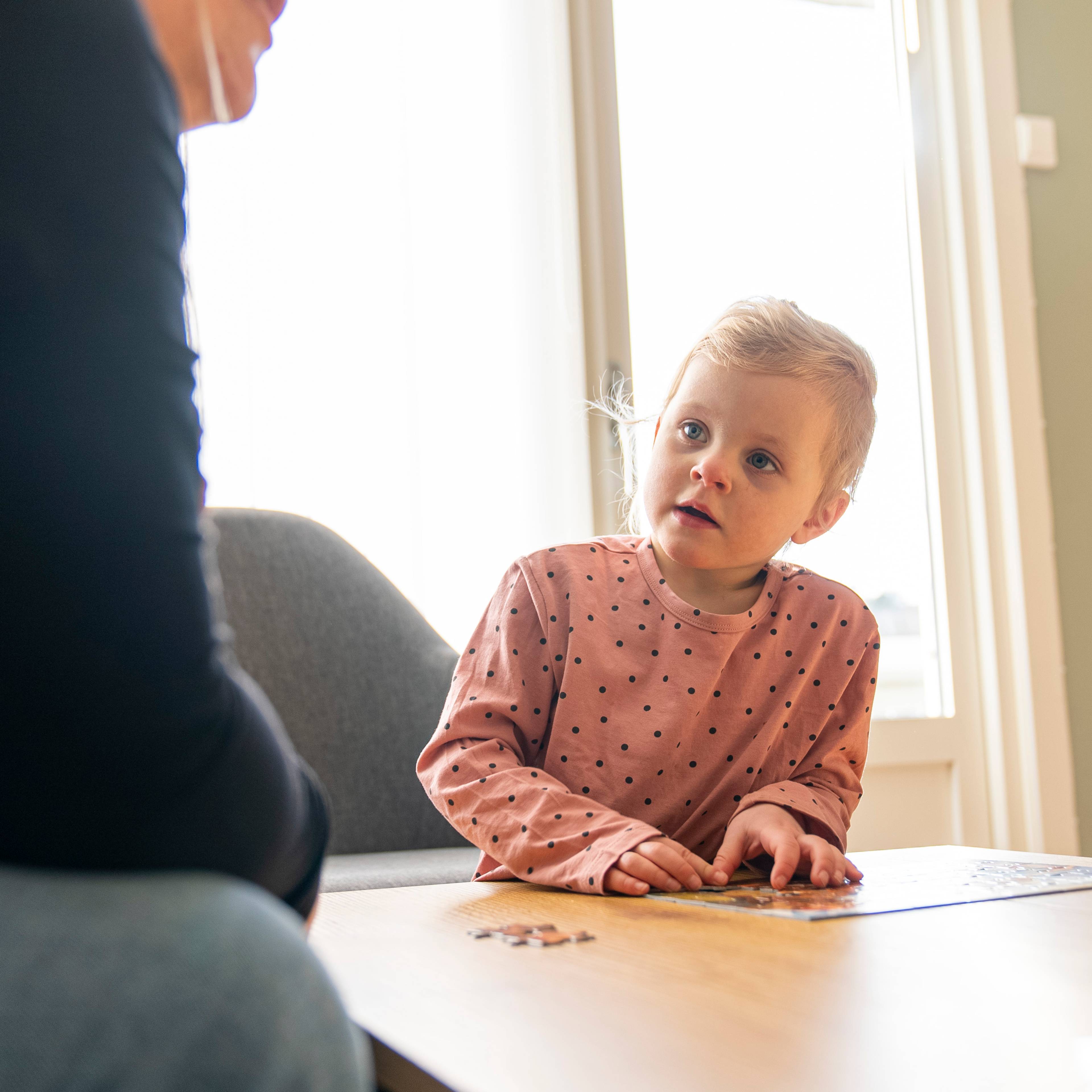 En liten jente ser mot moren som sitter til venstre i bildet.