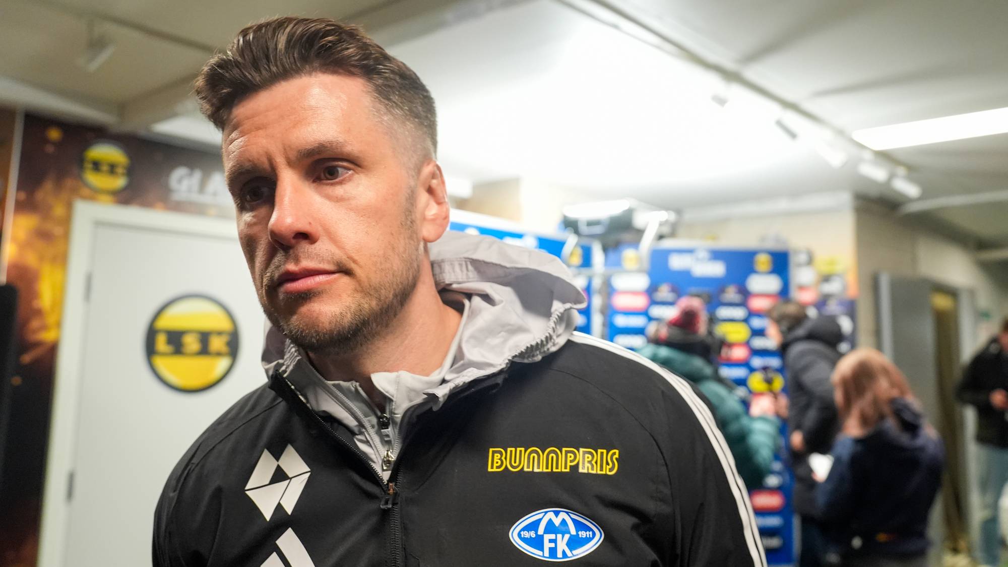 Trener for Molde FK, Erling Moe, ser til siden i et intervju med LSK-logo i bakgrunnen. (Bildebeskrivelsen er laget av en KI-tjeneste)