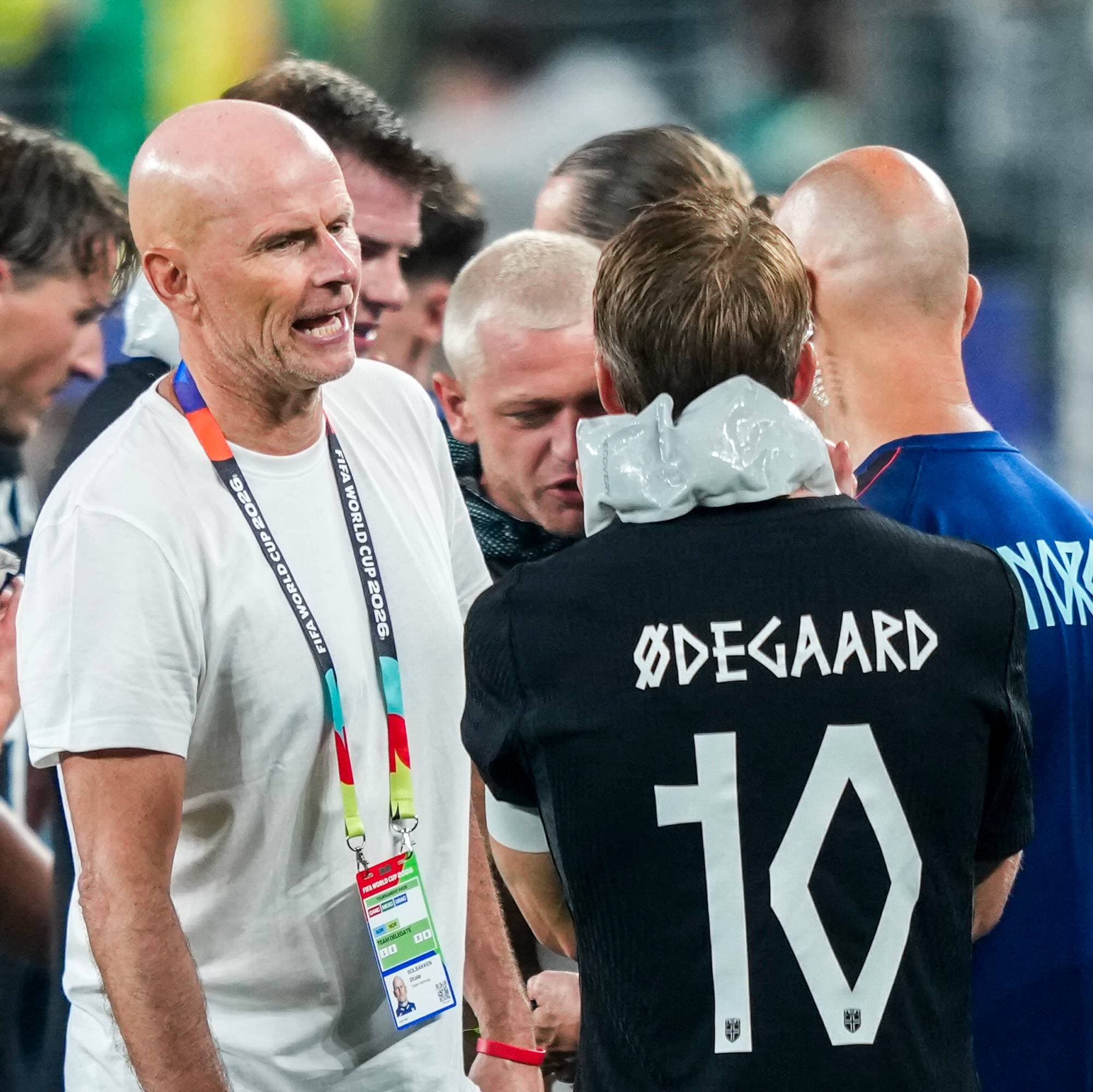 Landslagstrener Ståle Solbakken snakker med norske fotballspillere på banen etter en kamp. (Bildebeskrivelsen er laget av en KI-tjeneste)