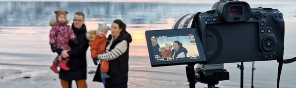 Bilde av filmsettet der Annika Rose Jensen og familien står på ei strand i Narvik med hav og fjell i bakgrunn
