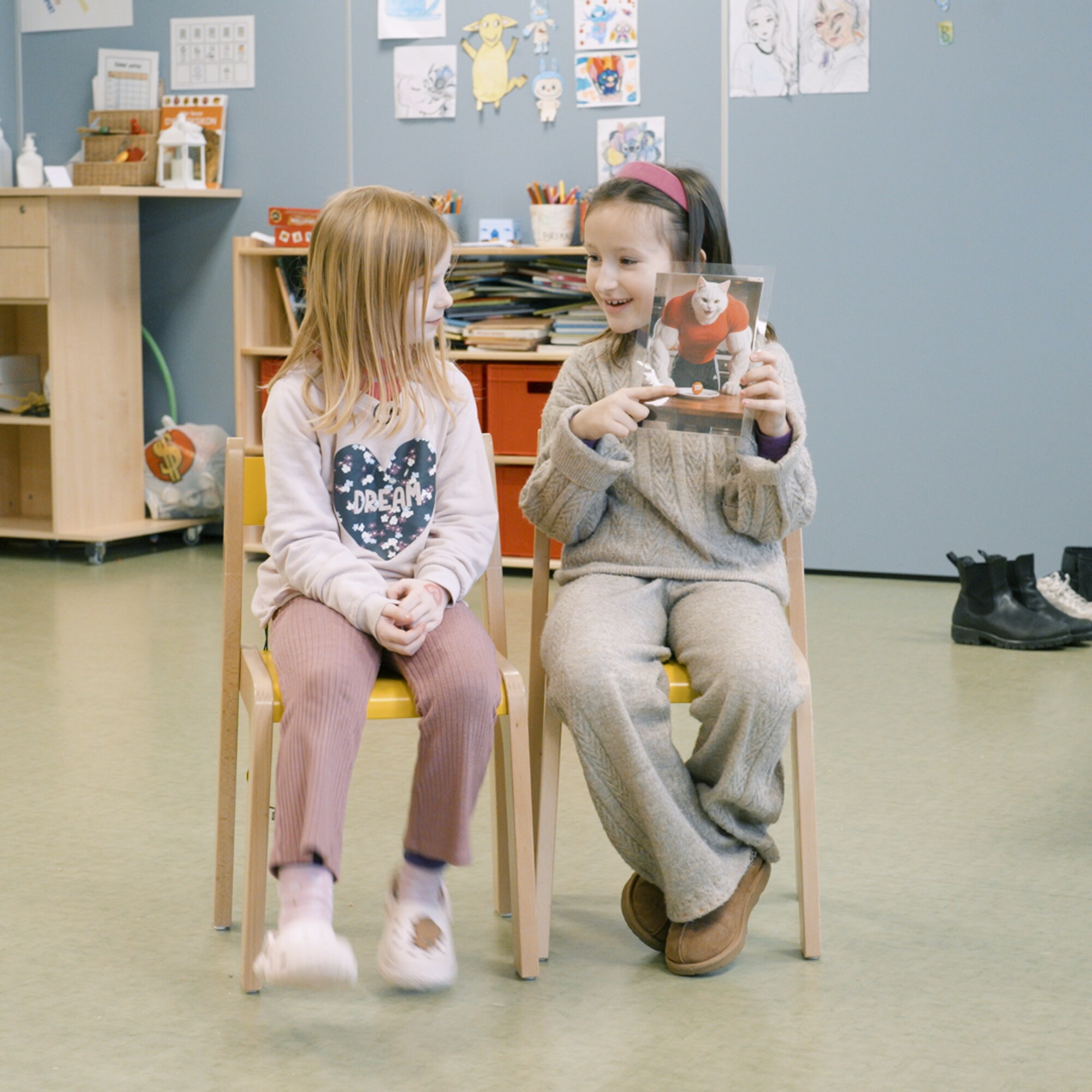 To skolebarn som ser på bilde av en katt med store muskler. 